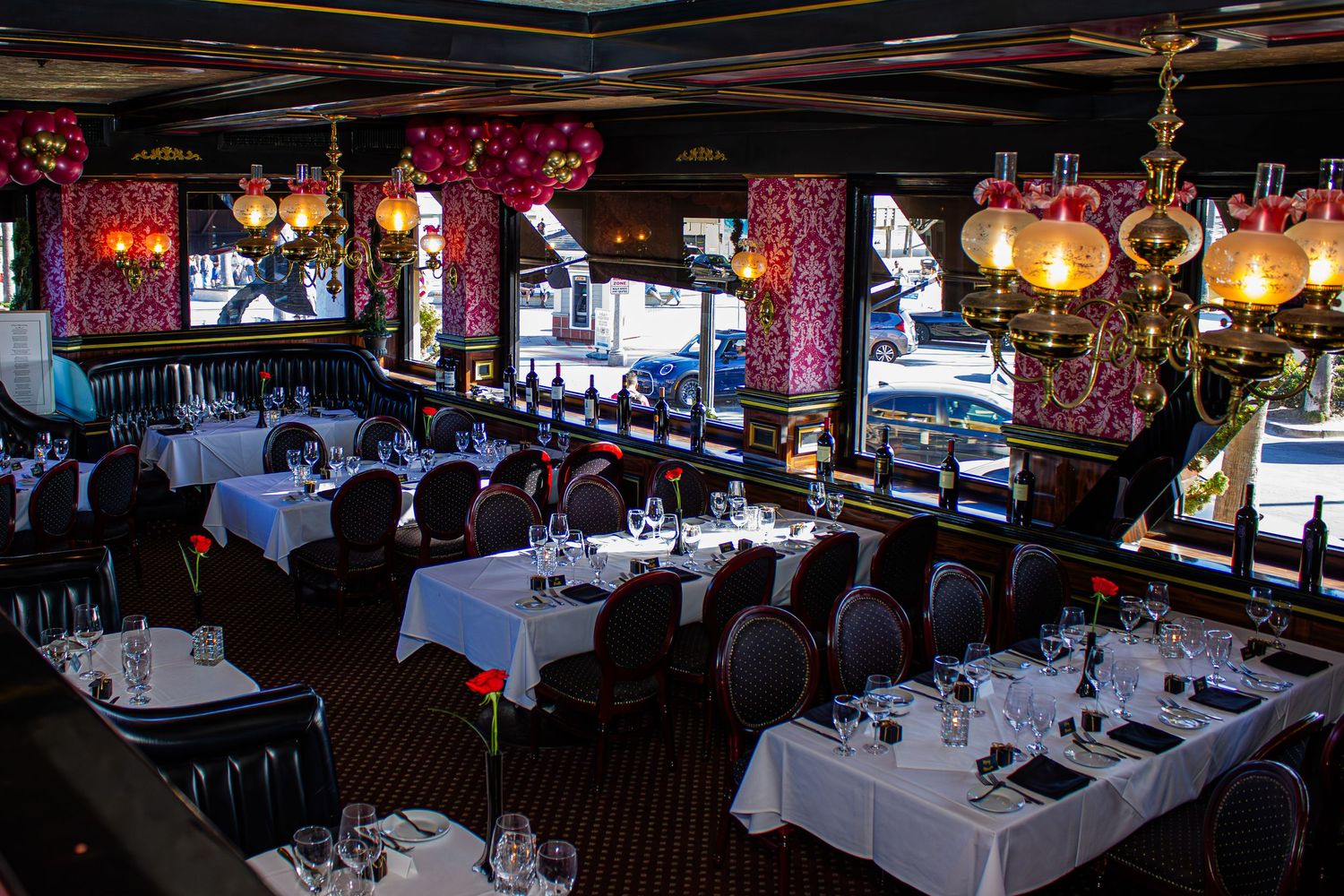 Elegant restaurant interior with white tablecloths, ornate decor, and chandelier lighting.