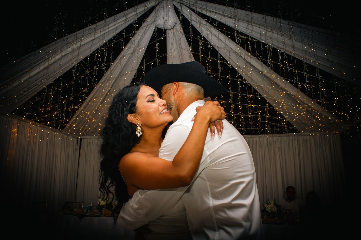 Romantic dance scene under twinkling lights and draped fabric ceiling.