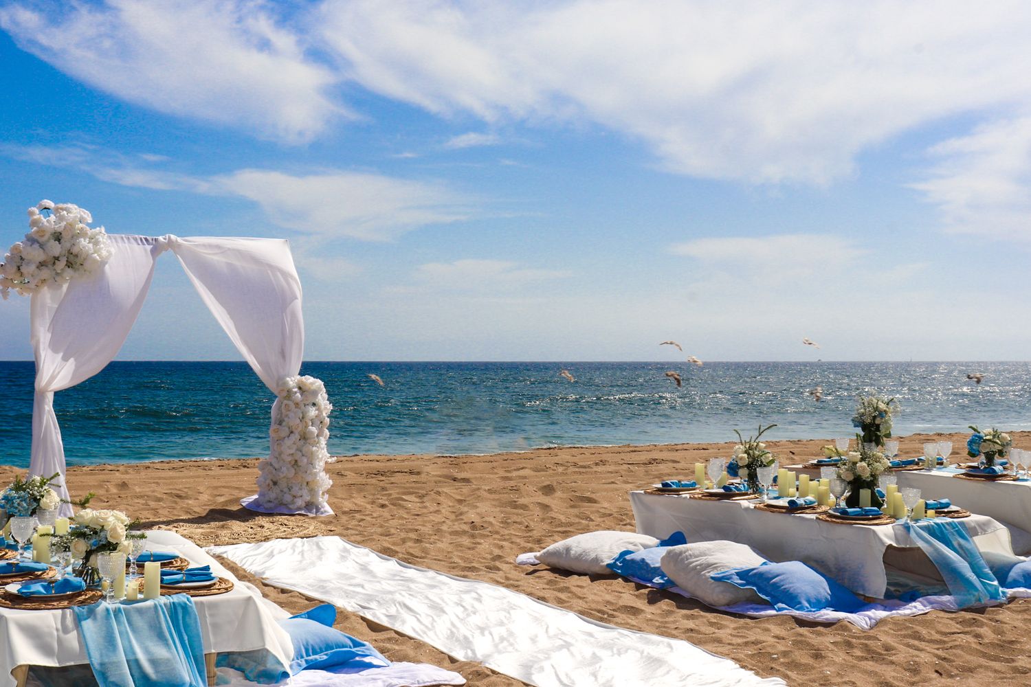 Scenic beach wedding setup with white chairs and blue ocean backdrop.