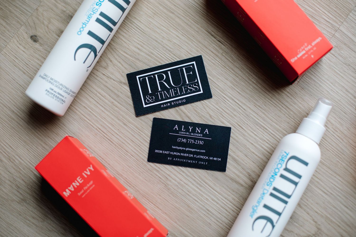 True Timeless and Alyna business cards surrounded by Unite and Mane Ivy hair products.