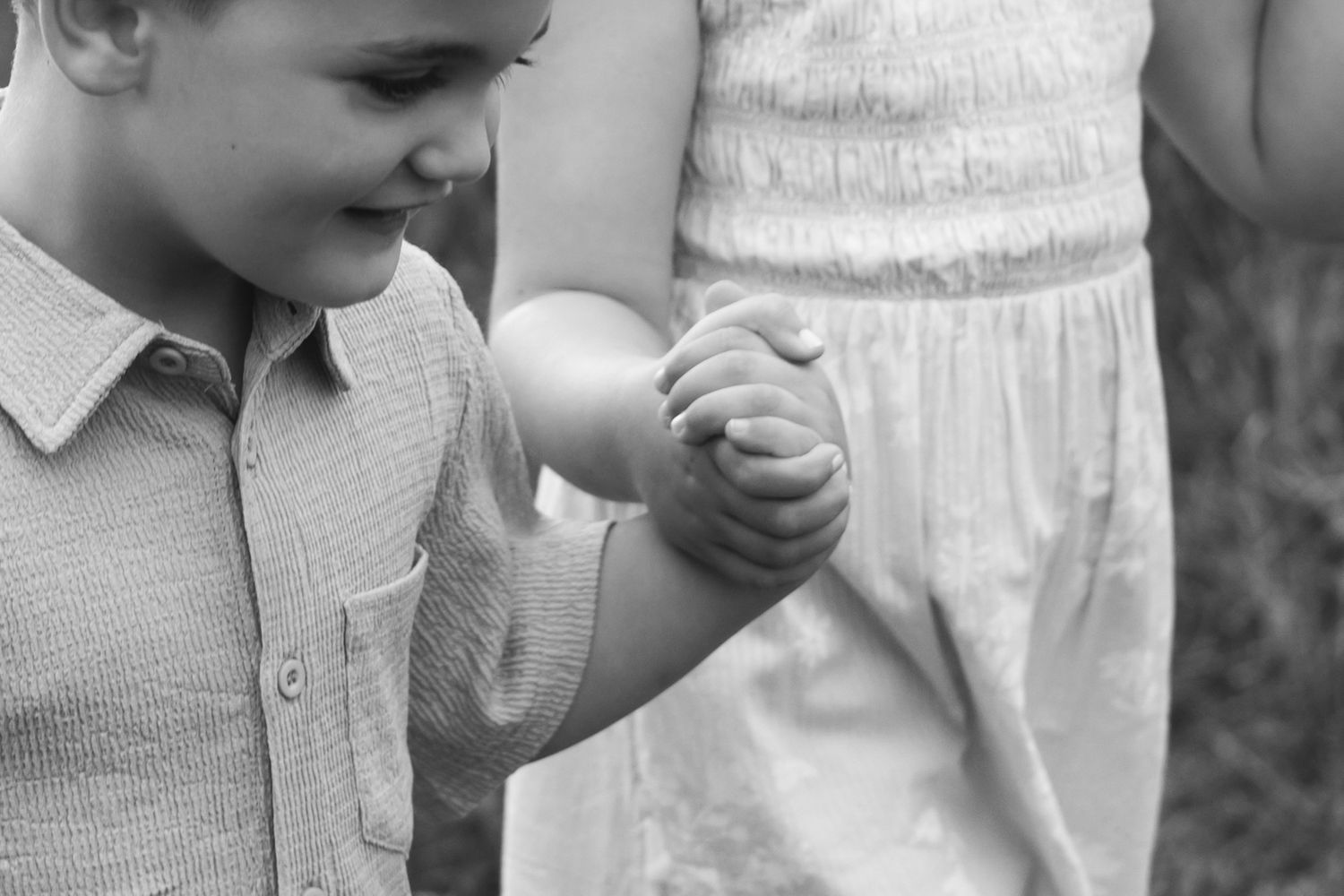 Black and white photo of a young boy holding hands with an adult in a garden setting.