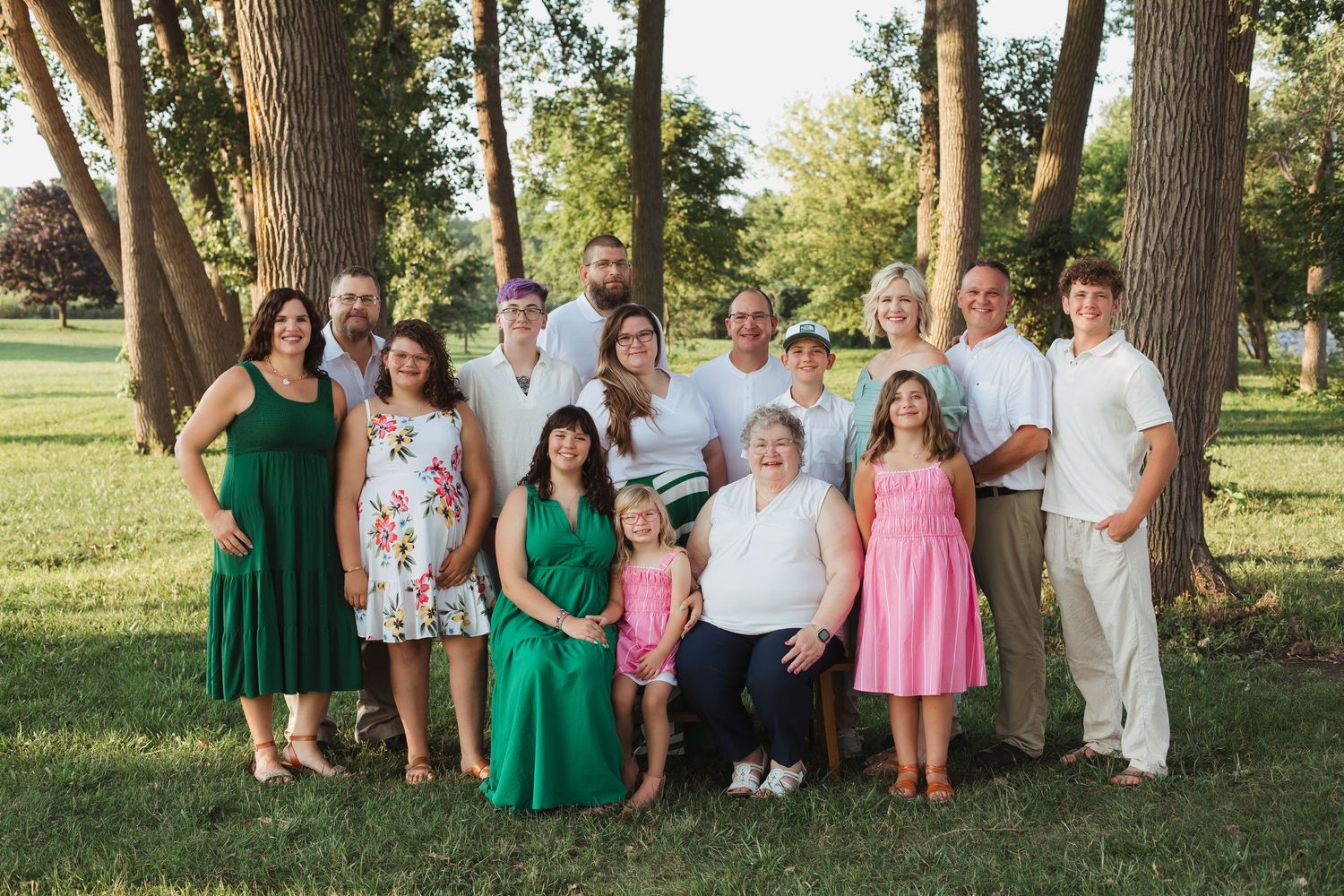 Multi-generational family photo session outdoors with coordinated green and pink outfits.