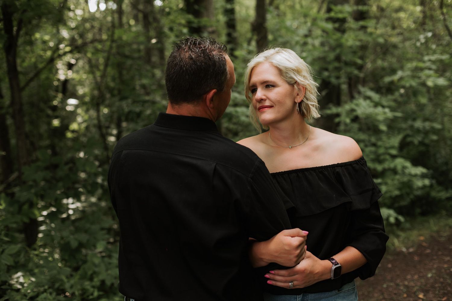 Couple sharing a tender moment together in a lush green forest.