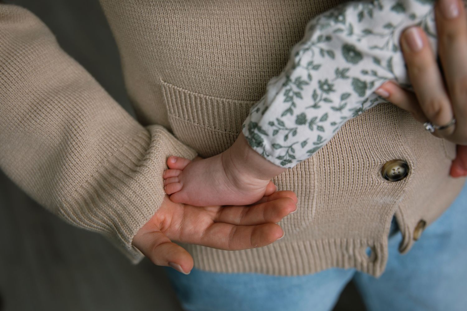 Close-up of tiny newborn baby foot resting in mothers gentle hand.