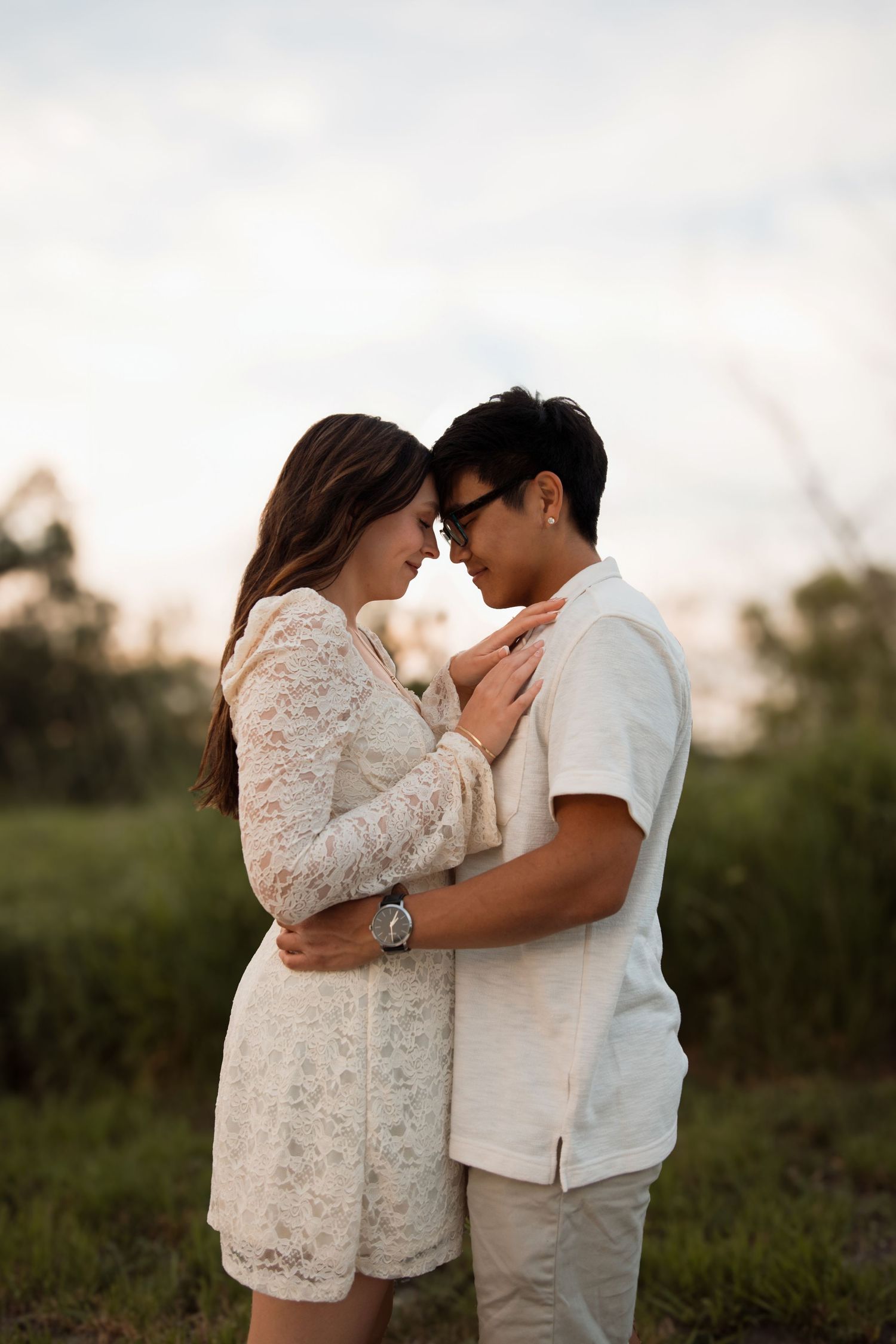 Couple embracing forehead-to-forehead in a romantic golden hour outdoor portrait.