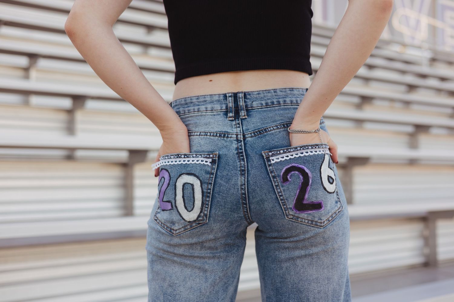 Close-up of senior 2026 custom embroidered jeans at stadium bleachers.