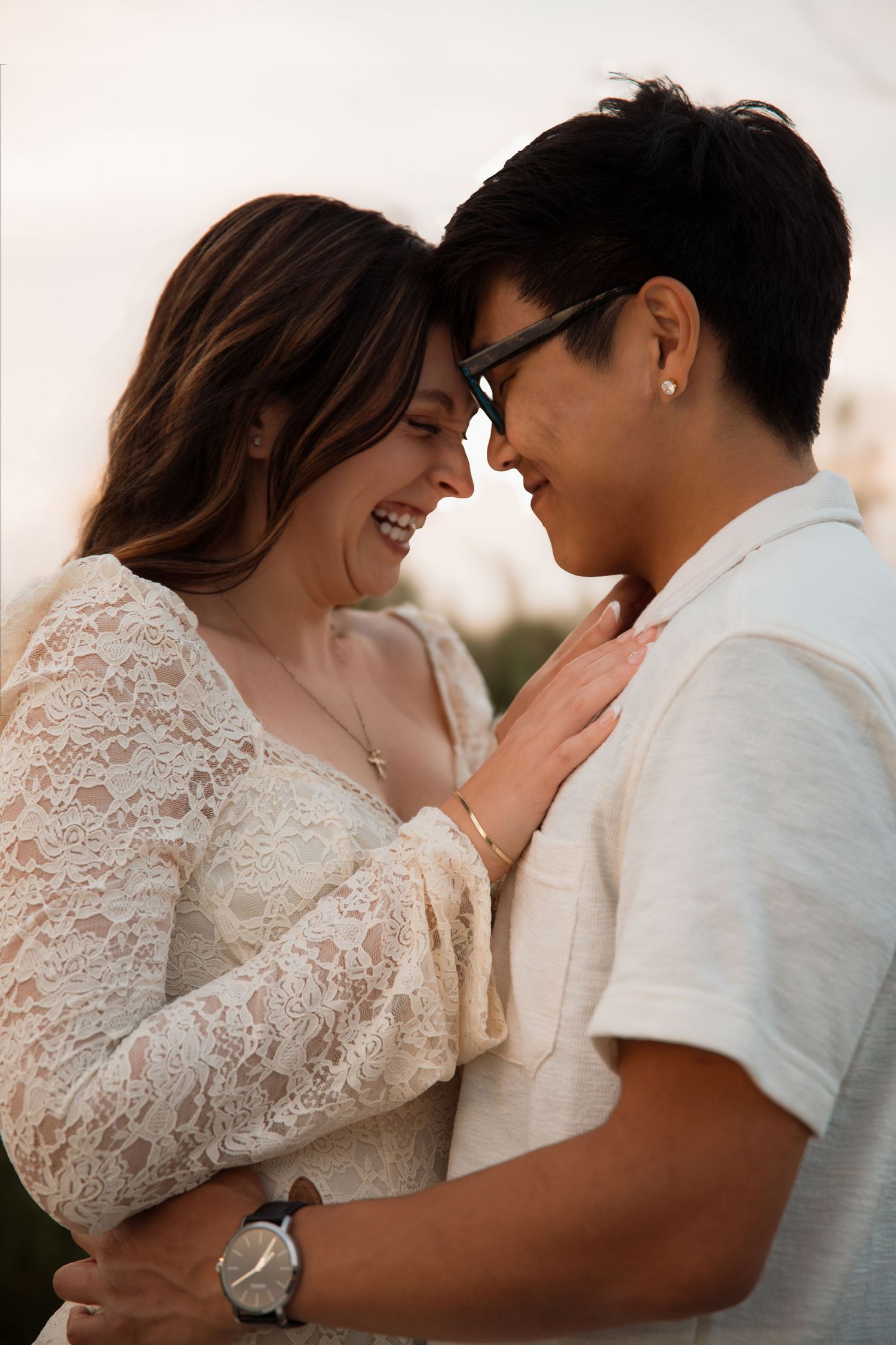 Joyful couple touching foreheads and smiling closely together during golden hour outdoors.