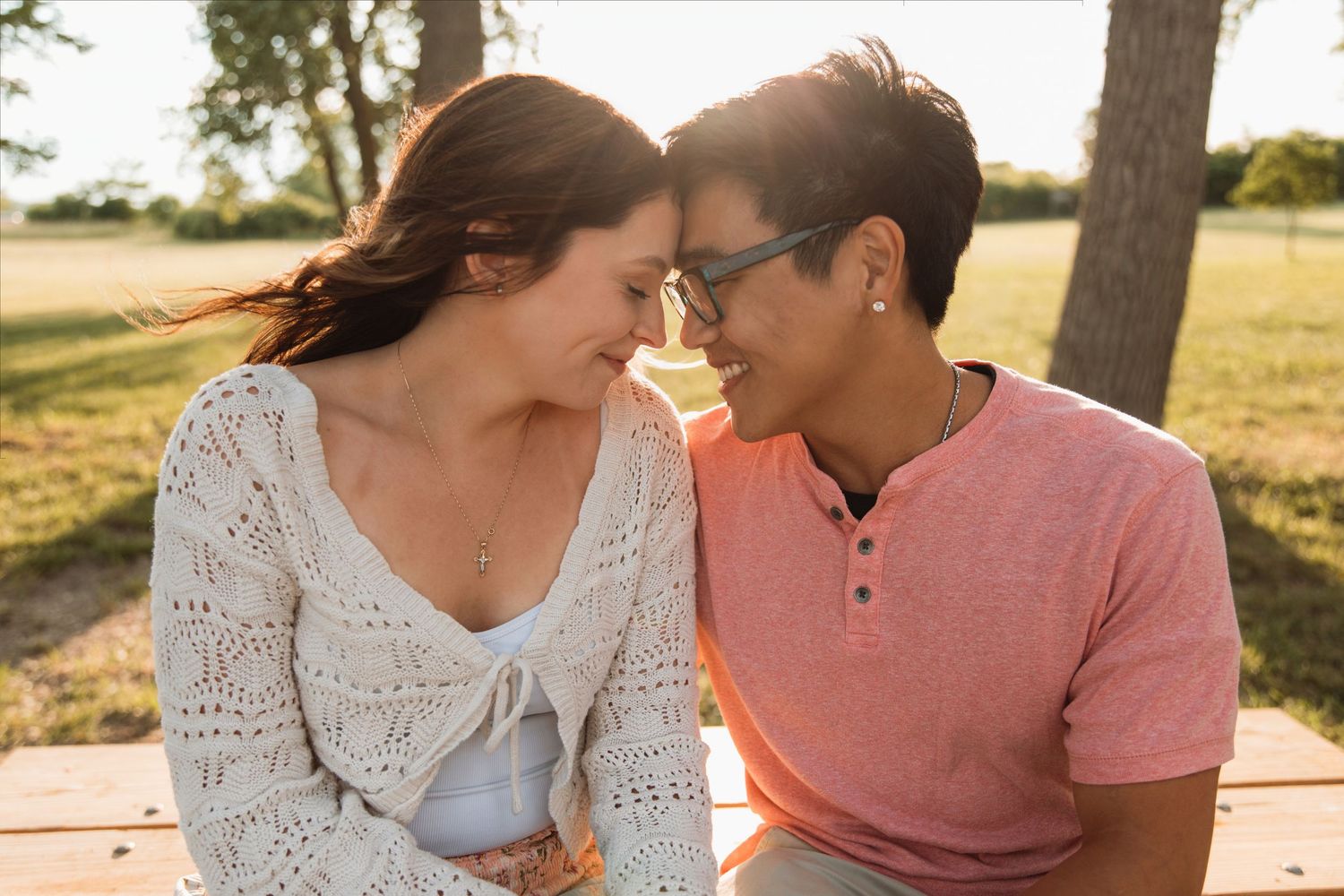 Young couple sharing an intimate moment sitting together outdoors in golden sunlight.