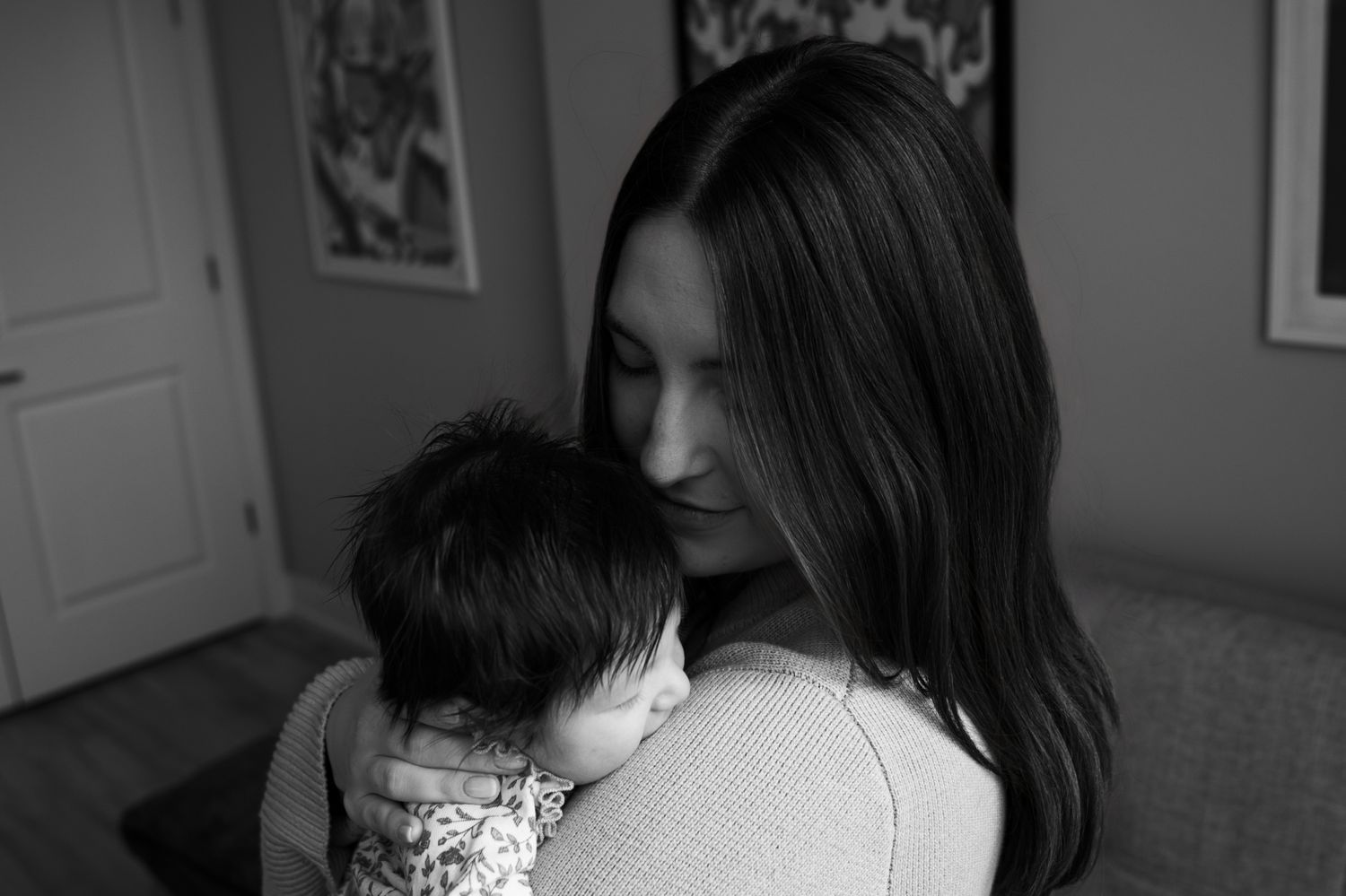 Black and white portrait of mother gently cradling and comforting newborn baby.
