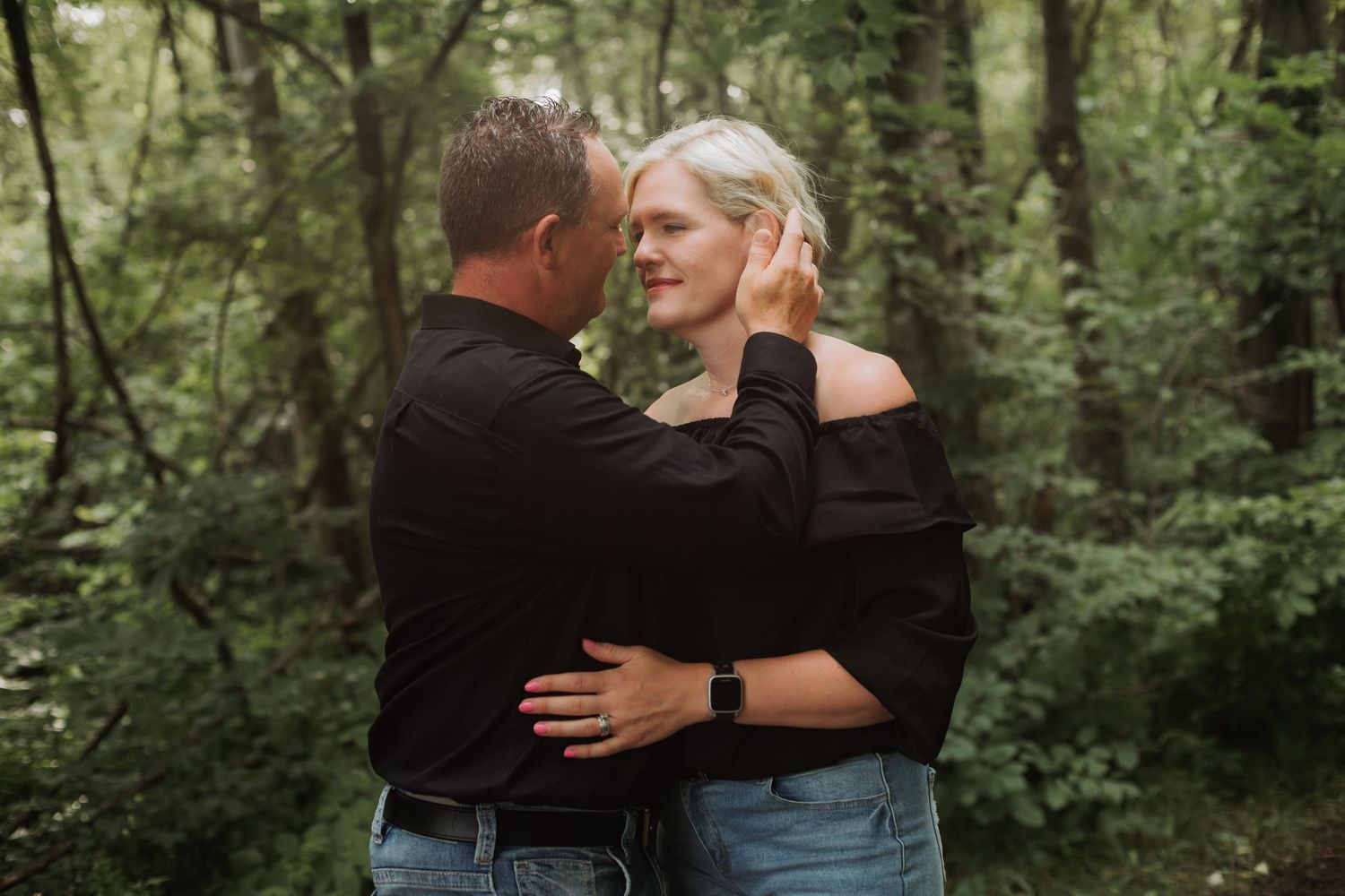 Man gently touching womans face in a romantic forest portrait.
