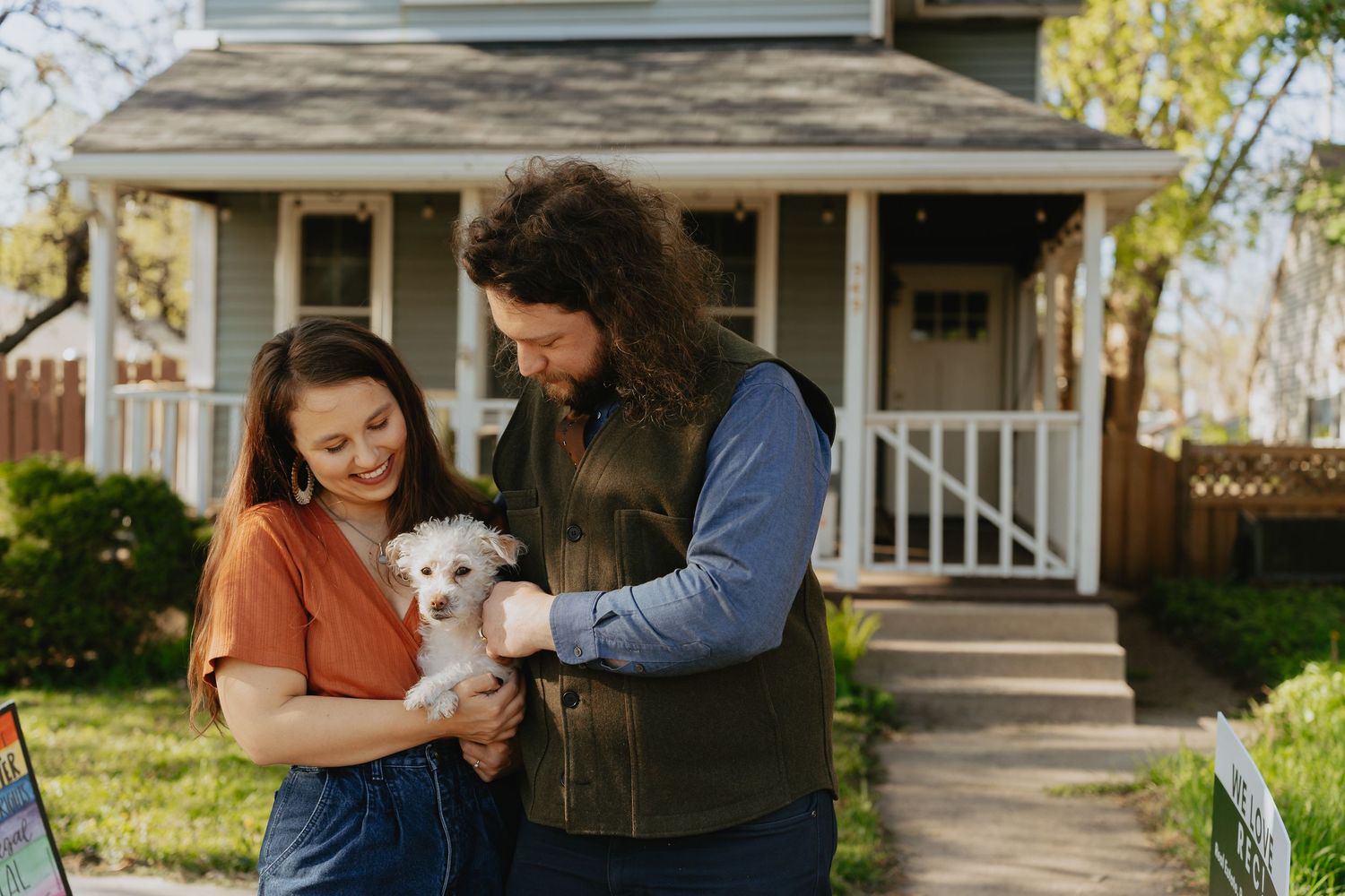 Couple posing in front of their house with their dog