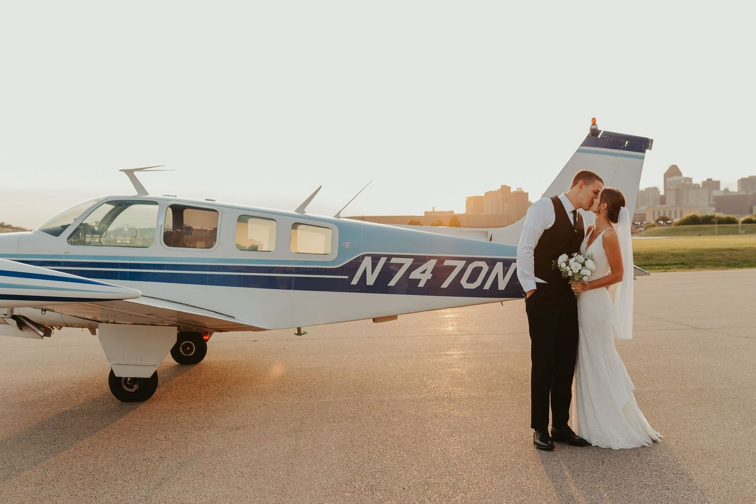 Wedding couple kisses in front of a small airplane at Holman's Table in St. Paul, Minnesota.