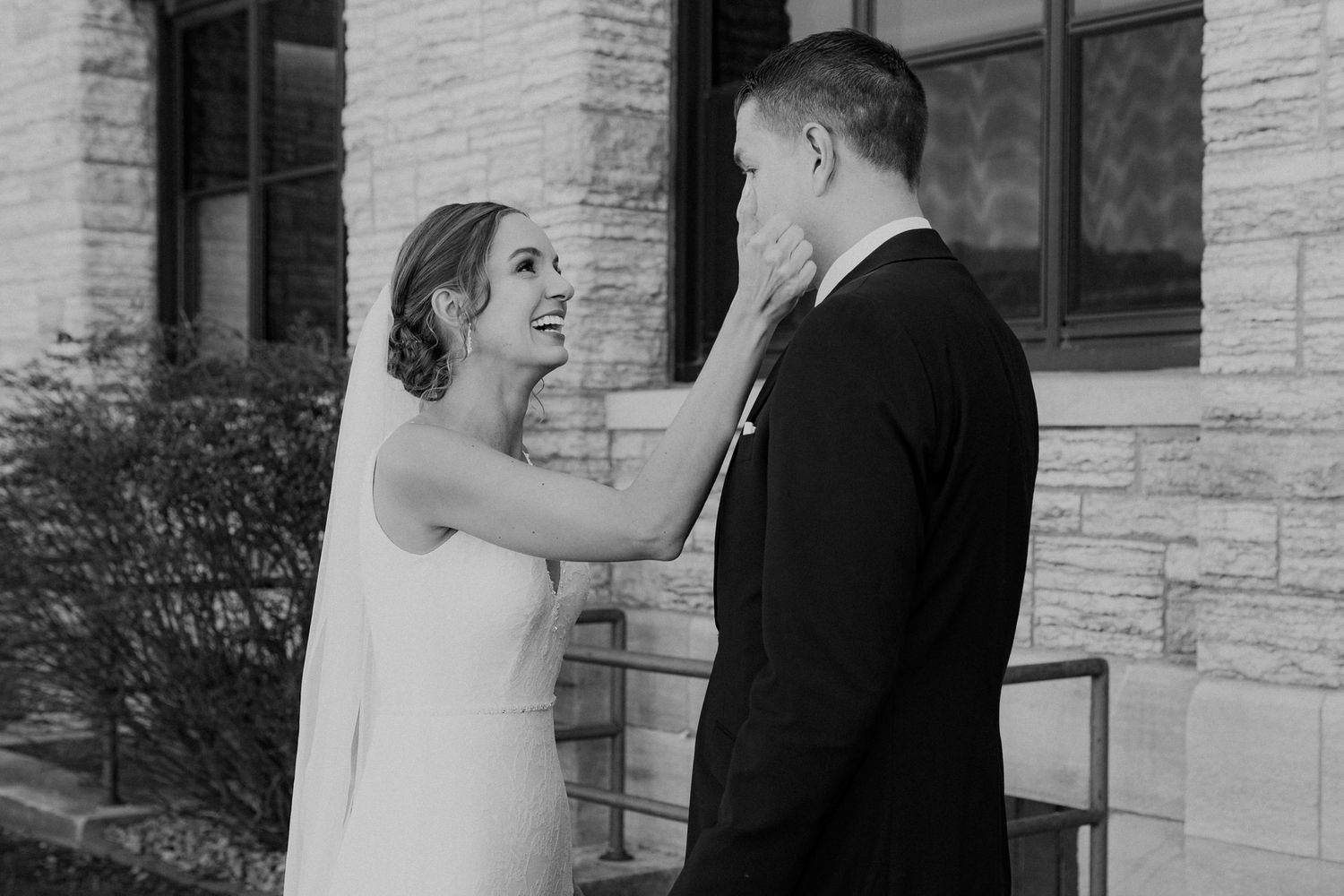 Bride wipes tears from groom's face during first look.