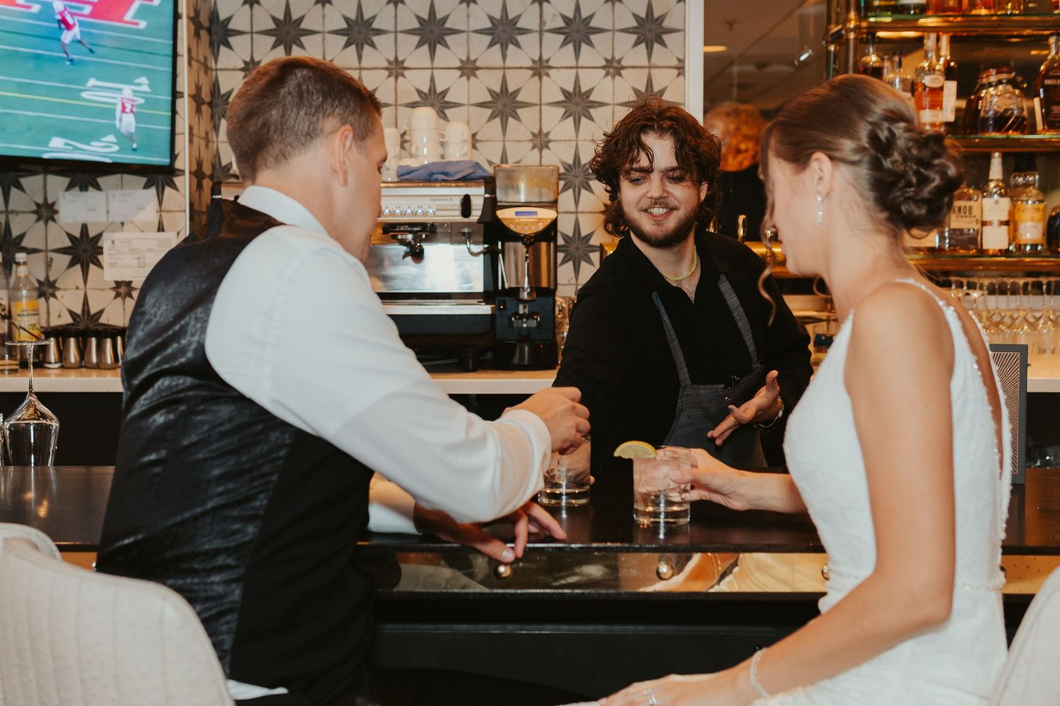 Bride and groom being served their favorite drink by the venue's bartender.