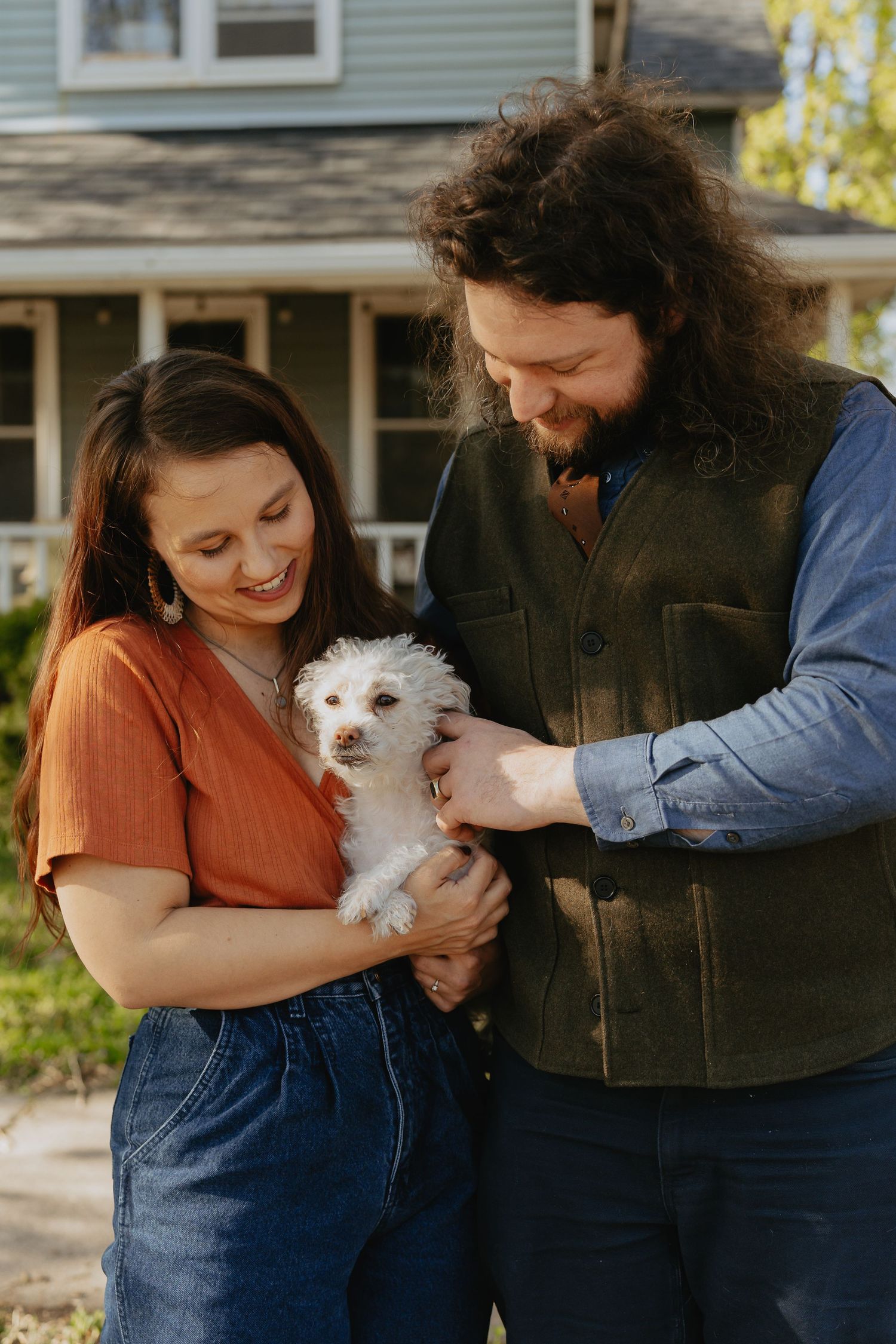 Couple posing in front of their house with their dog