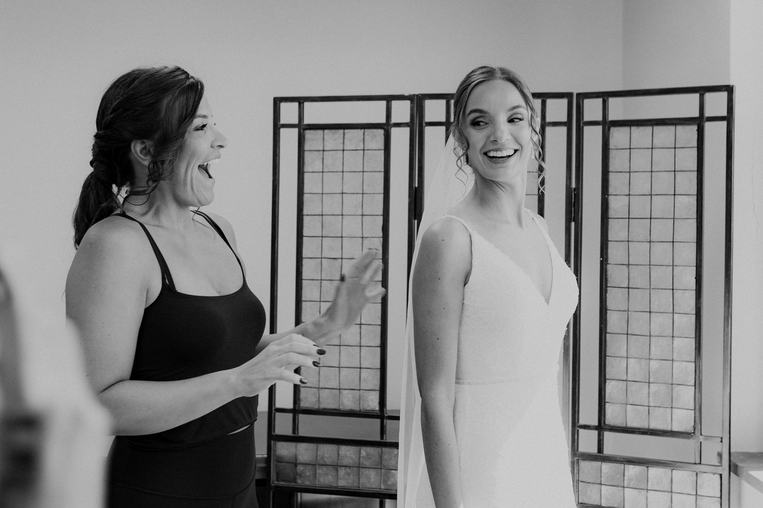 Bride's sister-in-law reacts joyfully to seeing bride with her veil on for the first time.