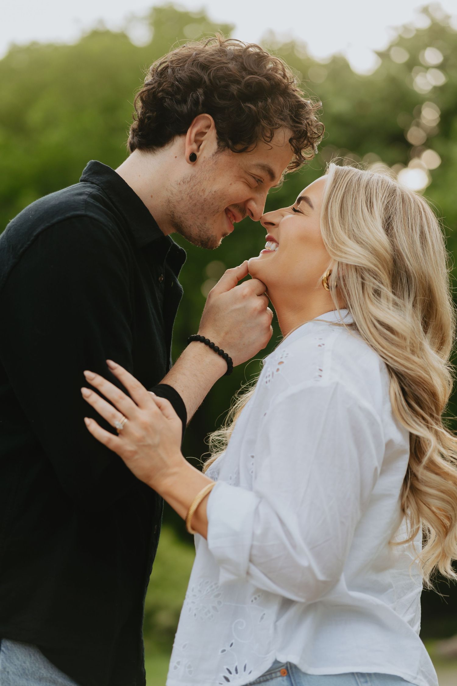 Man cupping woman's chin, couple smiling and touching noses