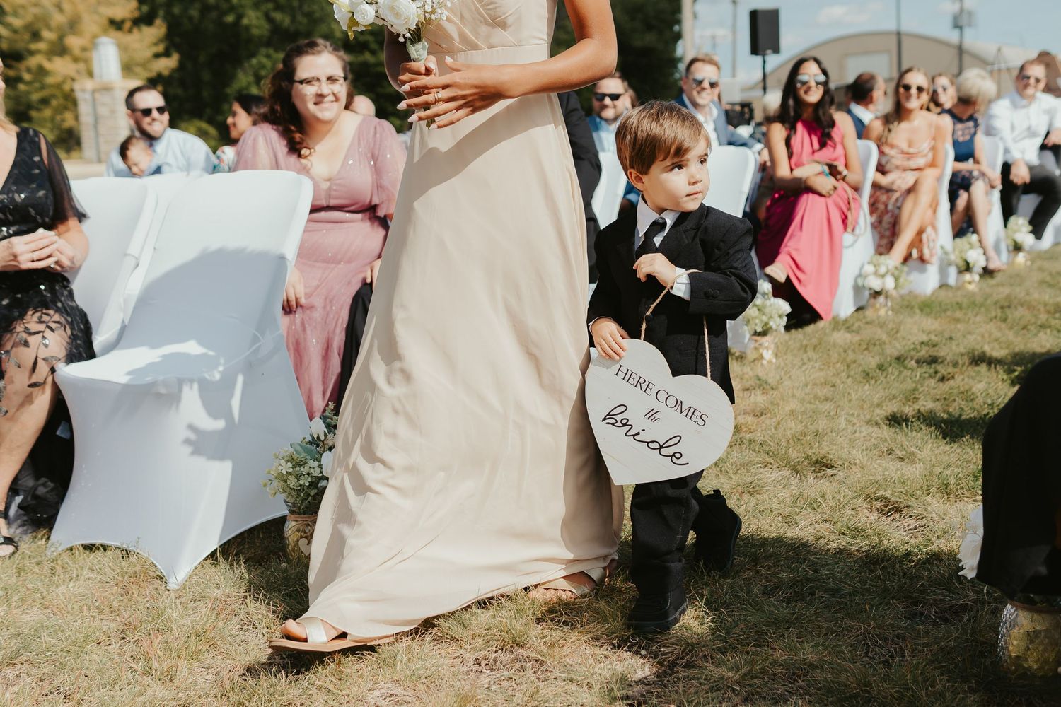 Ring bearer walking down the aisle with a sign that says, 