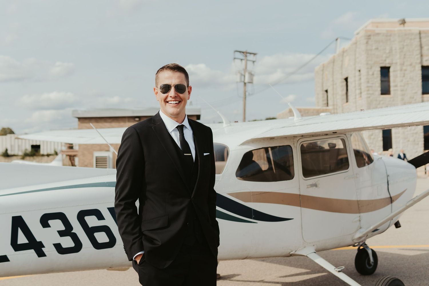 Groom posing with a private plane outside the venue.
