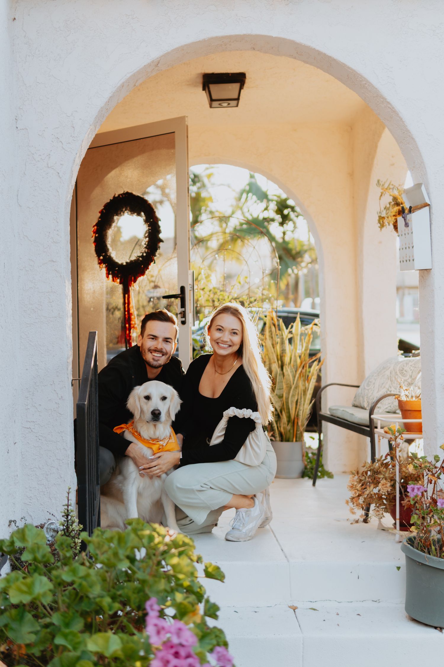 Couple posing with their dog on their front porch