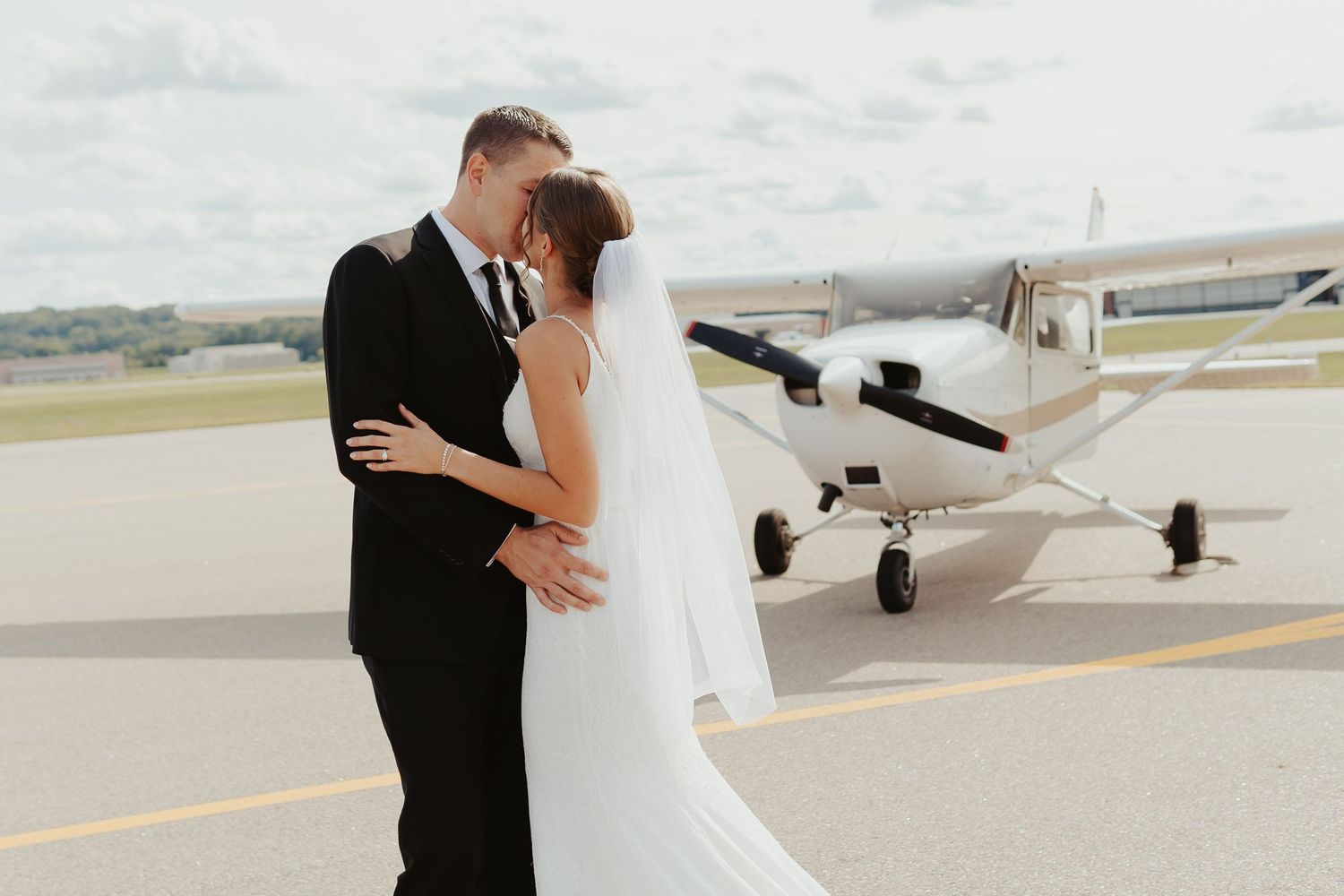 Bride and groom in front of a private plane outside the venue.