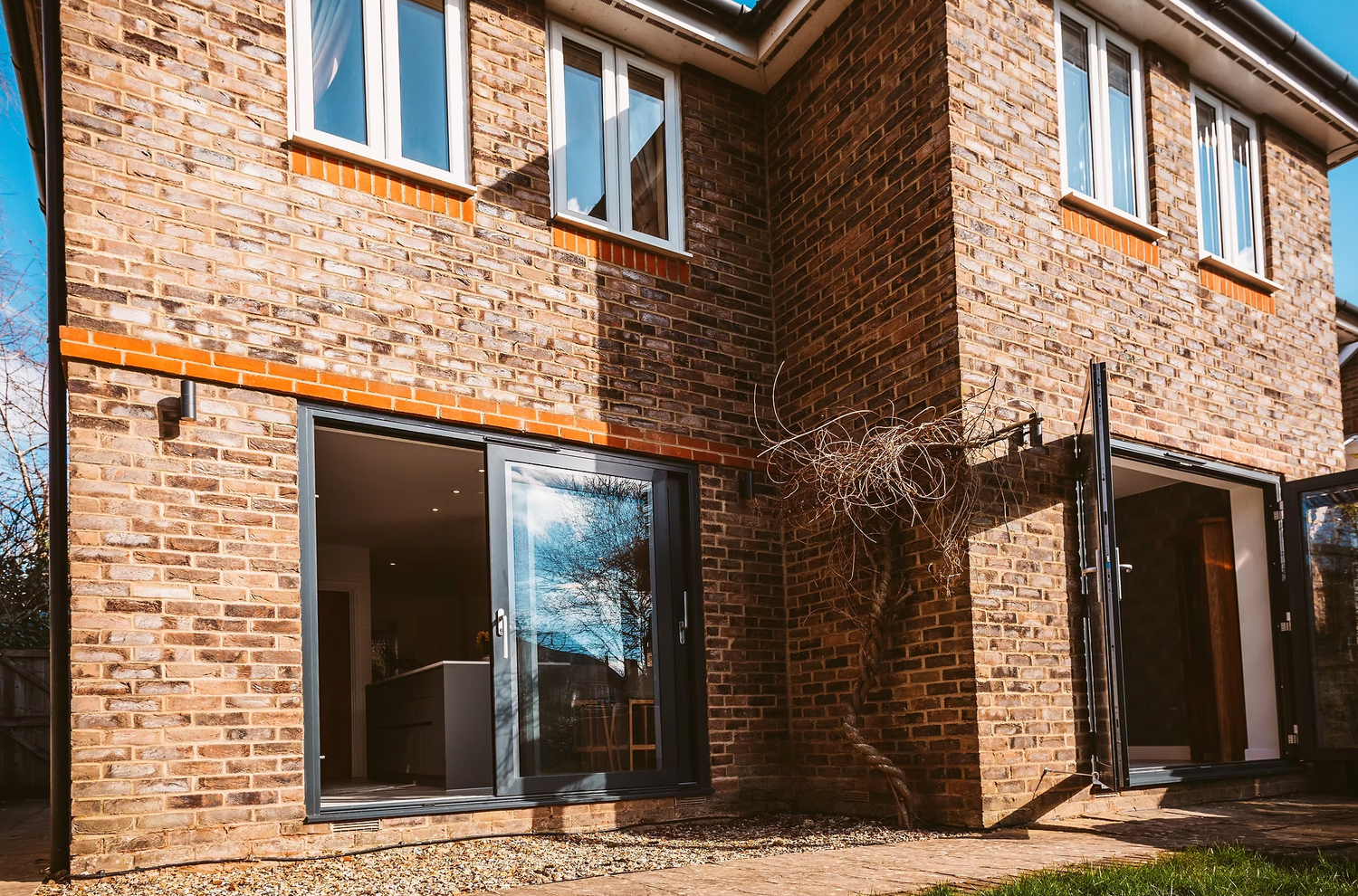 Modern apartment building exterior with exposed brick walls and large windows along a residential facade.