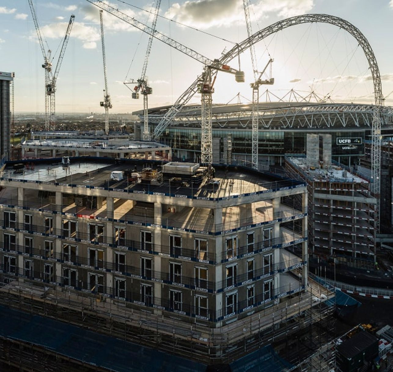 Aerial view of construction site near Wembley Stadium with cranes and partially built residential building in London.