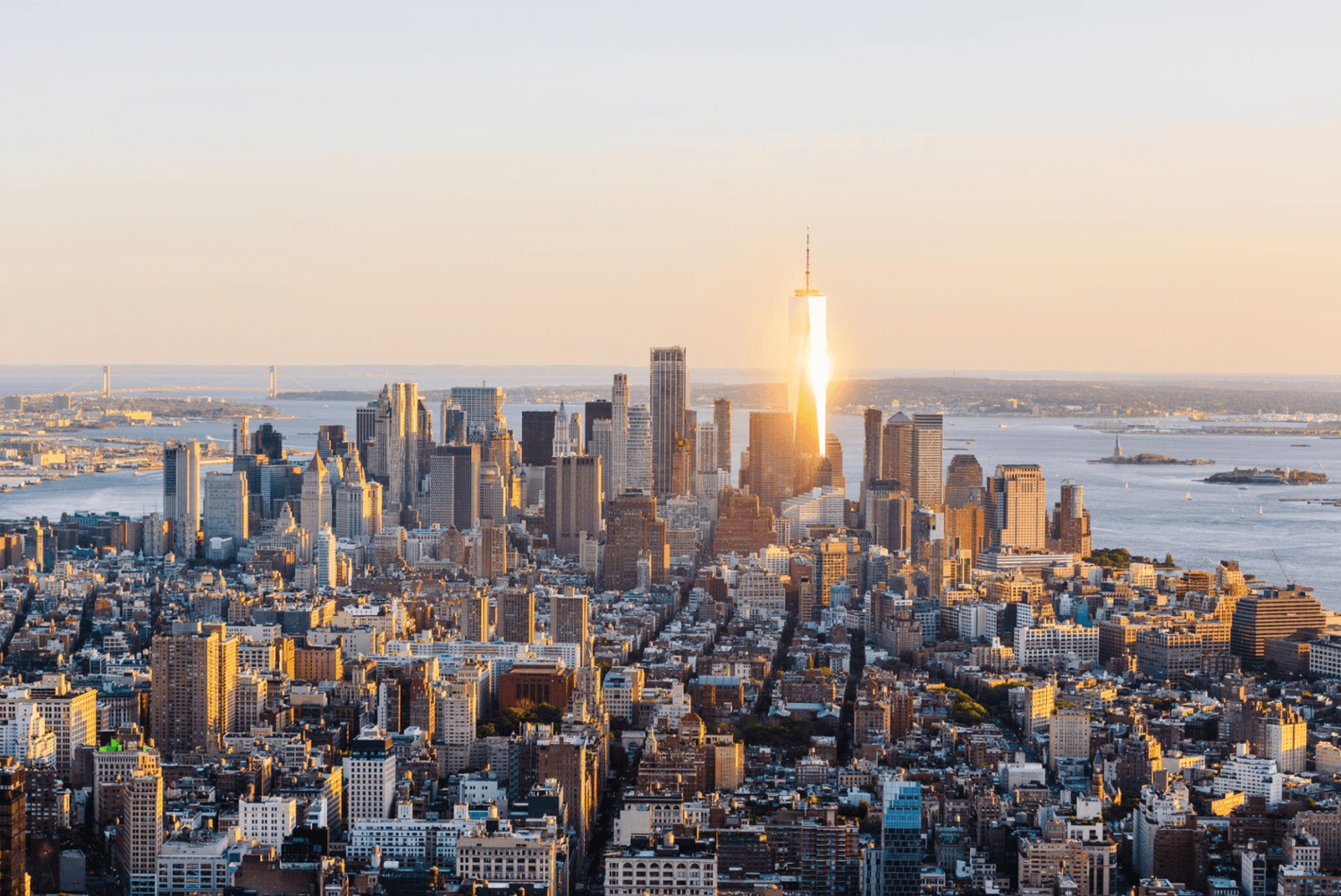 Aerial sunset view of Manhattan skyline with One World Trade Center gleaming in golden light, New York City.