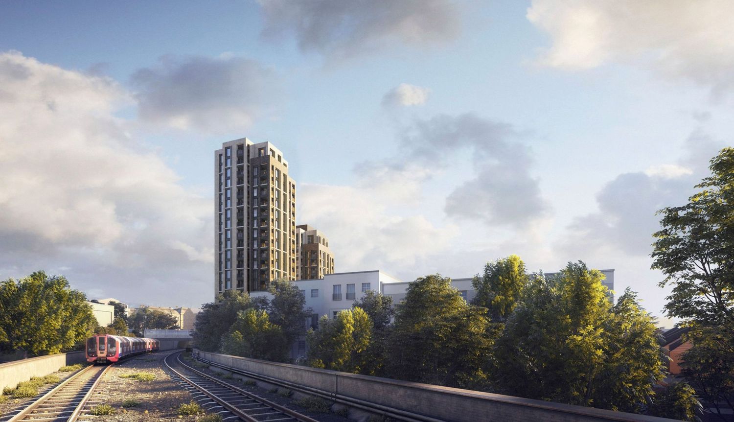 Modern high-rise residential tower beside railway tracks, surrounded by trees and lower buildings under a cloudy sky.