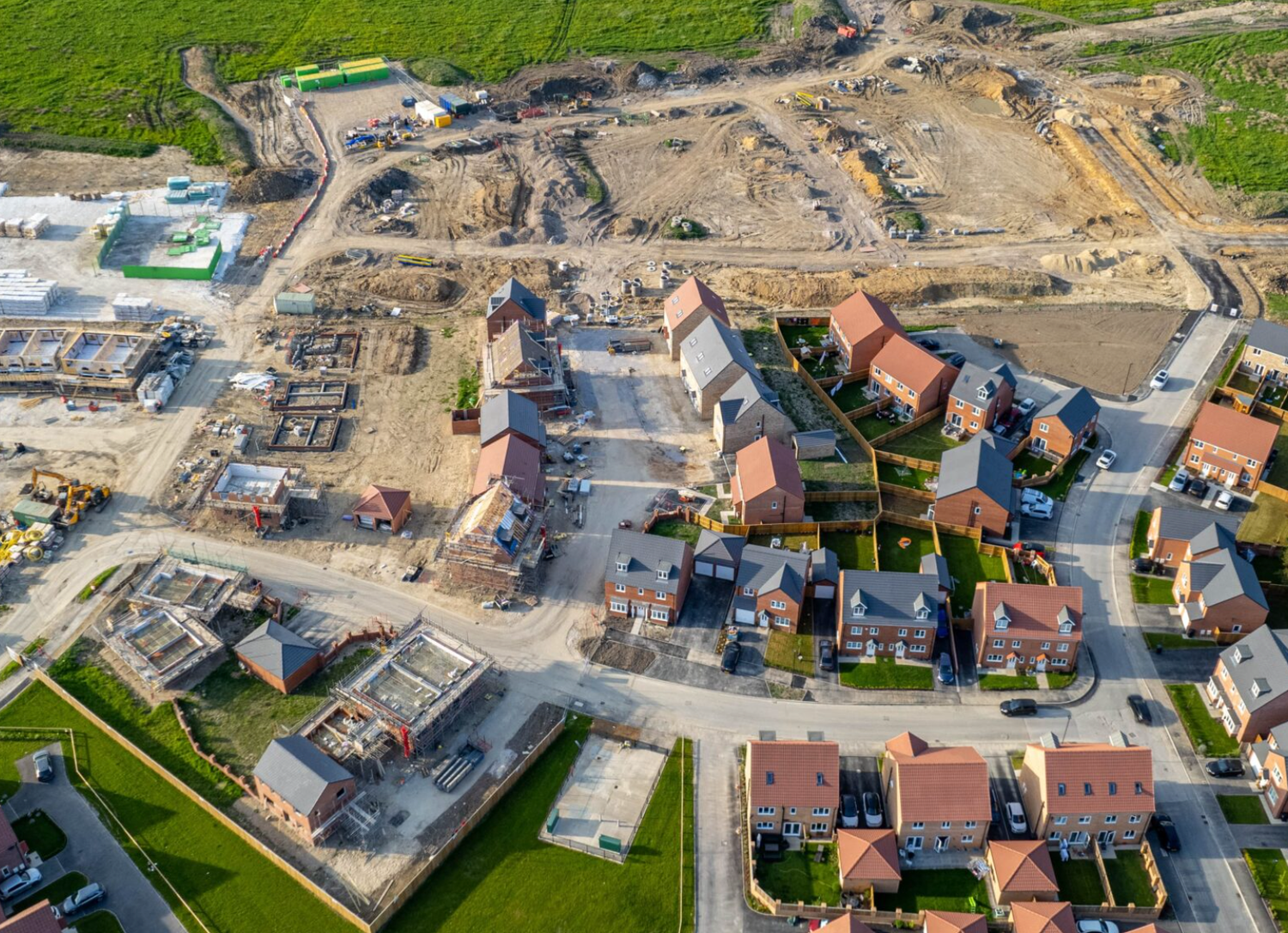 Aerial view of a new residential housing development under construction with completed homes and active building sites.