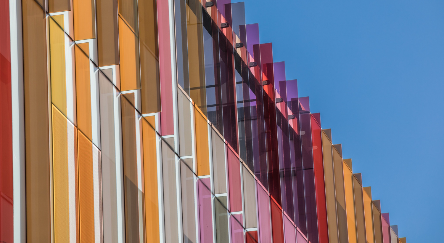 Colorful vertical architectural elements in orange, purple and blue create a modern geometric pattern against the sky.