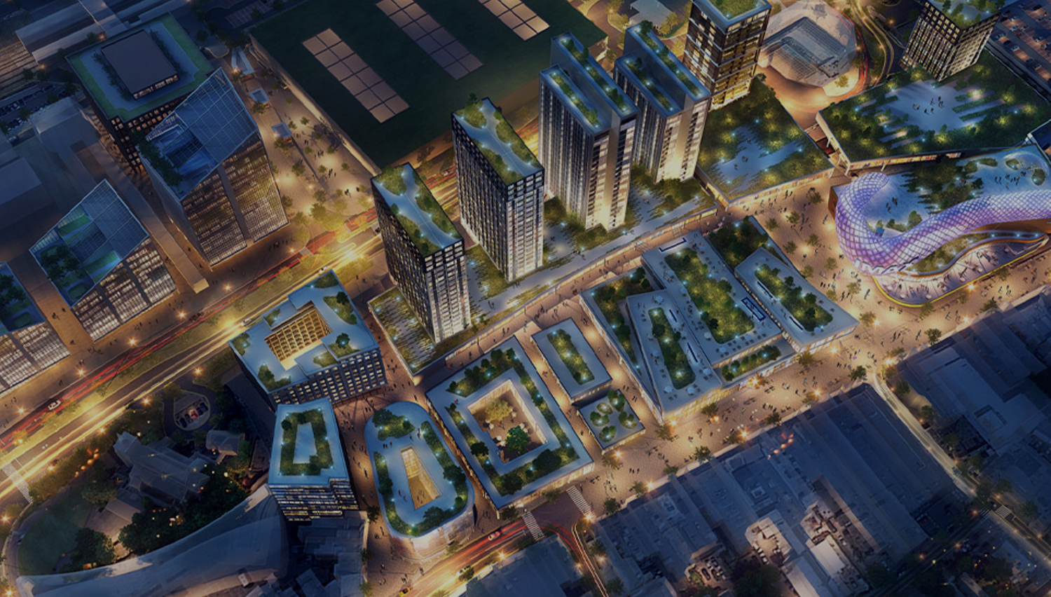 Aerial night view of modern urban development with illuminated skyscrapers, green rooftops, and bustling city streets.