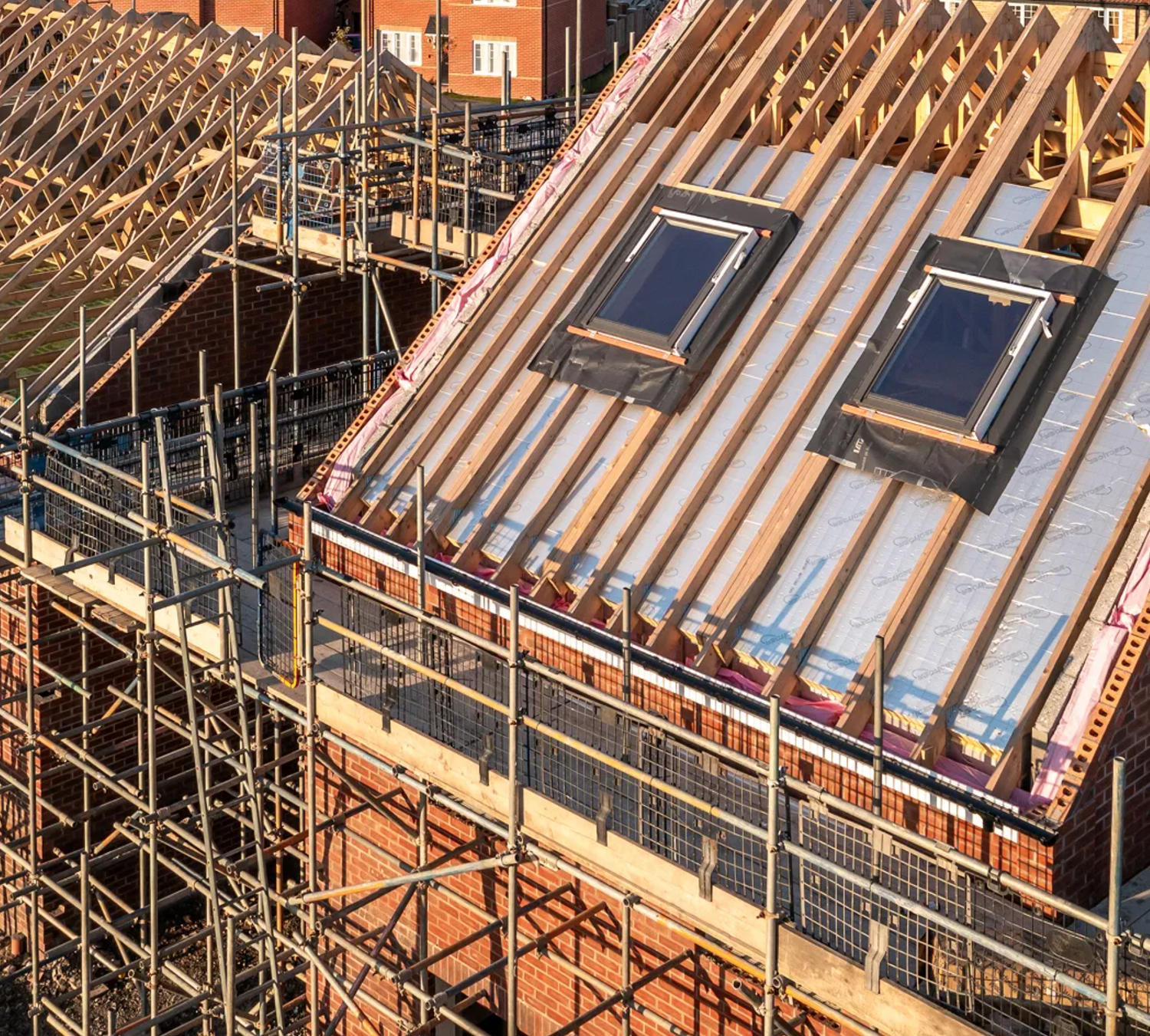 New residential building under construction with copper roof, skylights, and wooden scaffolding.
