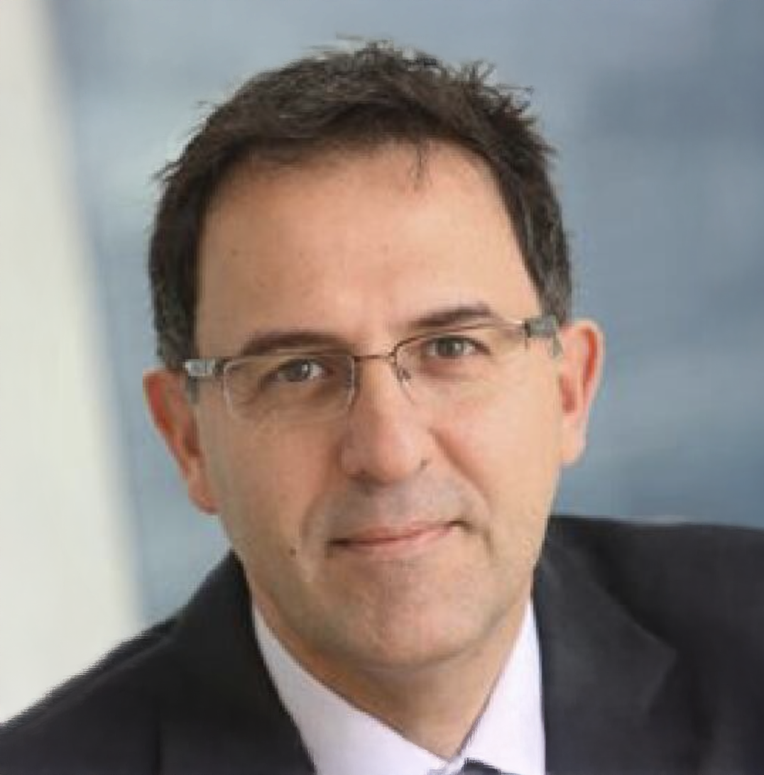 Professional headshot of a middle-aged businessman wearing glasses and a dark suit, smiling confidently.