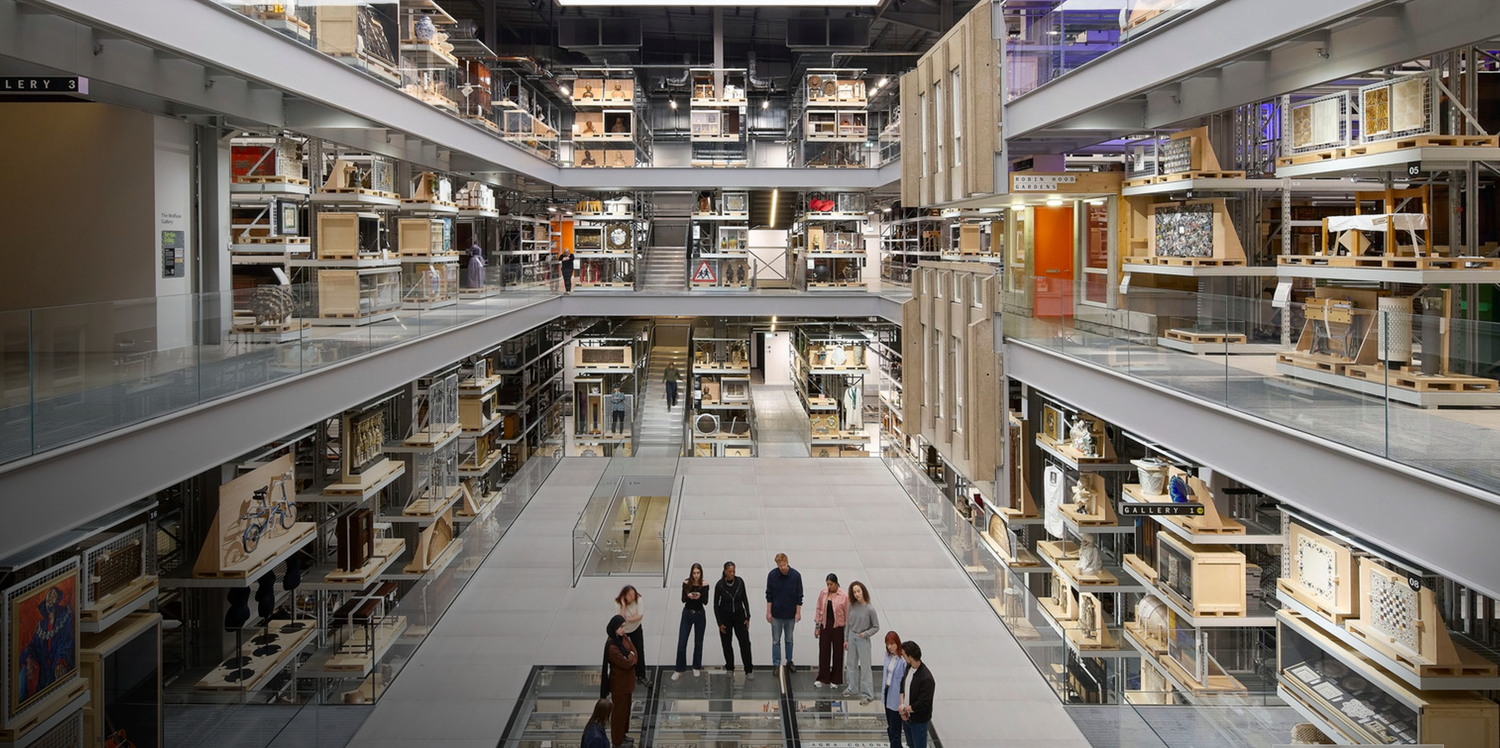 People standing in a vast multi-story library archive with tall shelving units filled with books and artifacts.