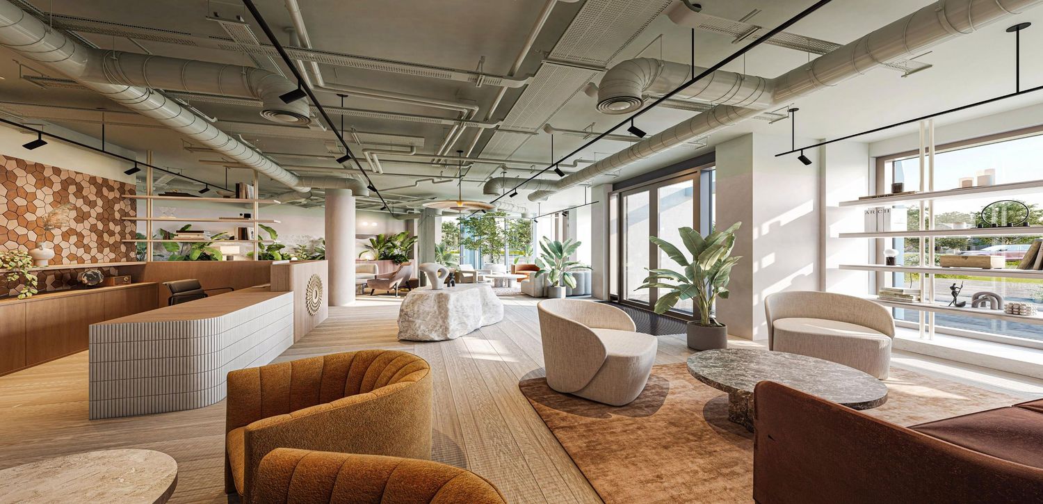 Modern open-plan coworking space with warm wood floors, lush plants, and stylish lounge seating in a bright, airy office.