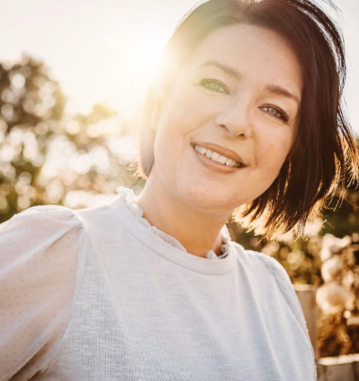 Sunlit portrait against natural outdoor backdrop with warm golden lighting.