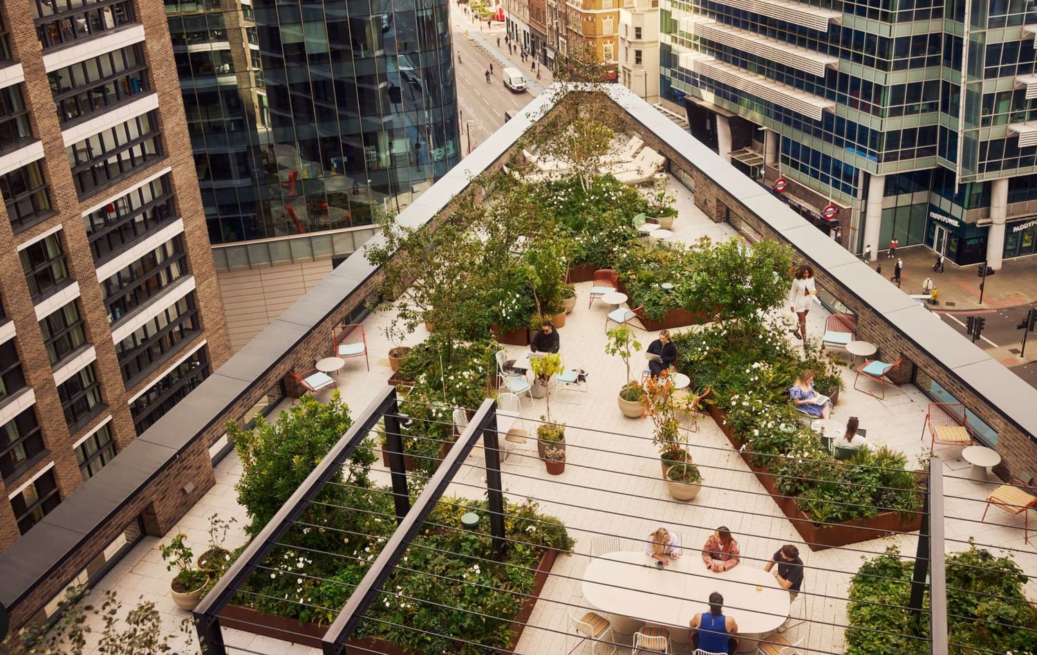 Aerial view of a lush rooftop garden with seating areas surrounded by tall city buildings.