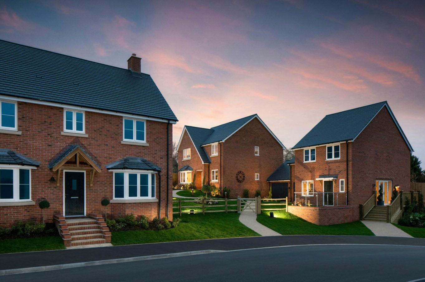 Row of modern brick houses at dusk with colorful sunset sky in a new residential development.