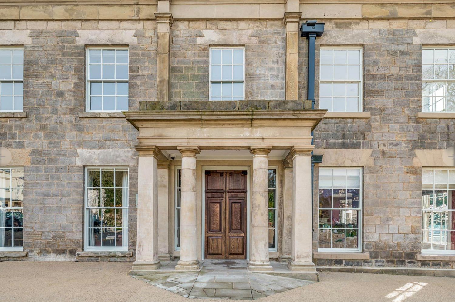Grand Georgian stone building entrance with classical columns, wooden door, and symmetrical sash windows.