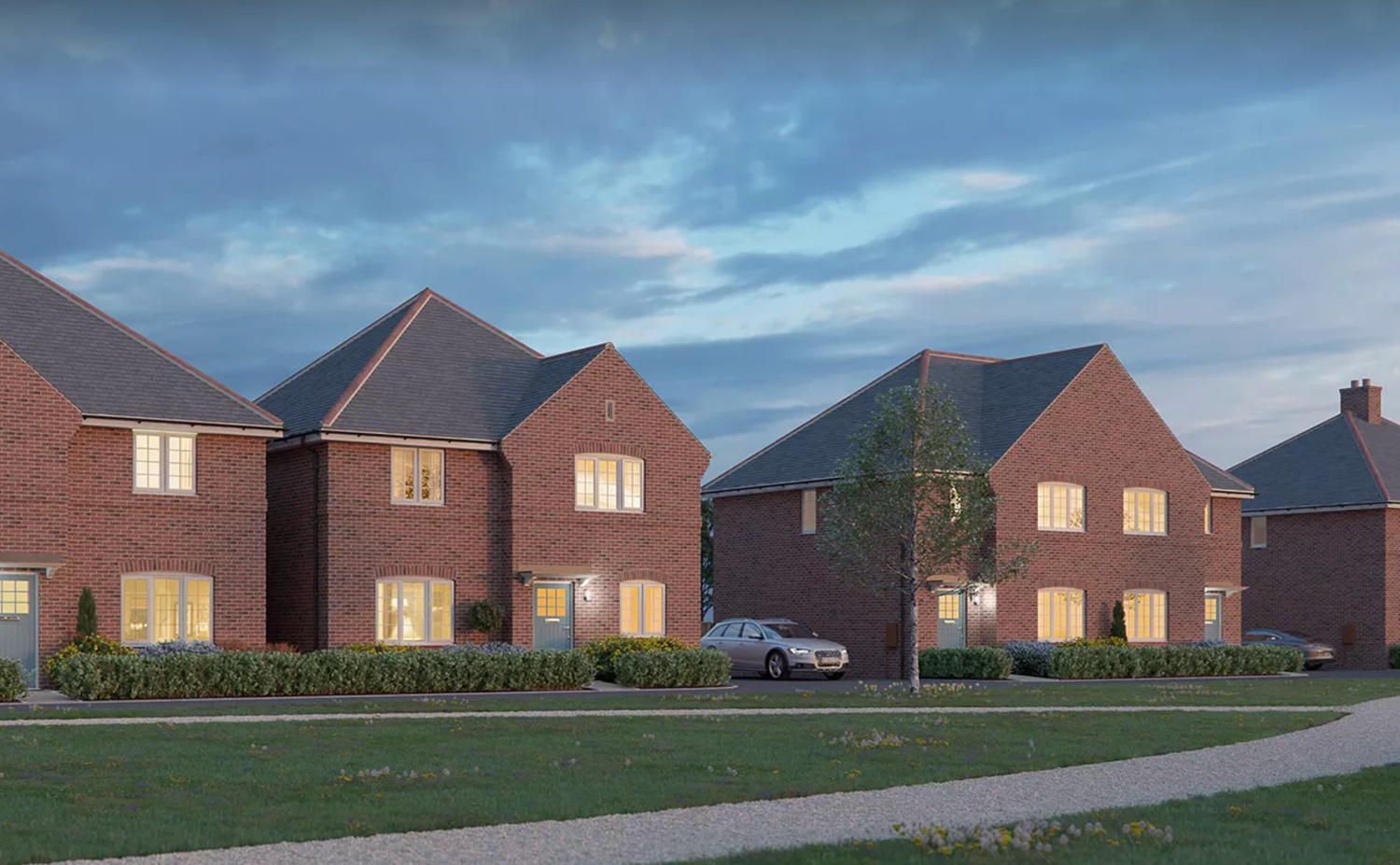 Modern residential development with a row of brick houses and driveways under a moody evening sky.
