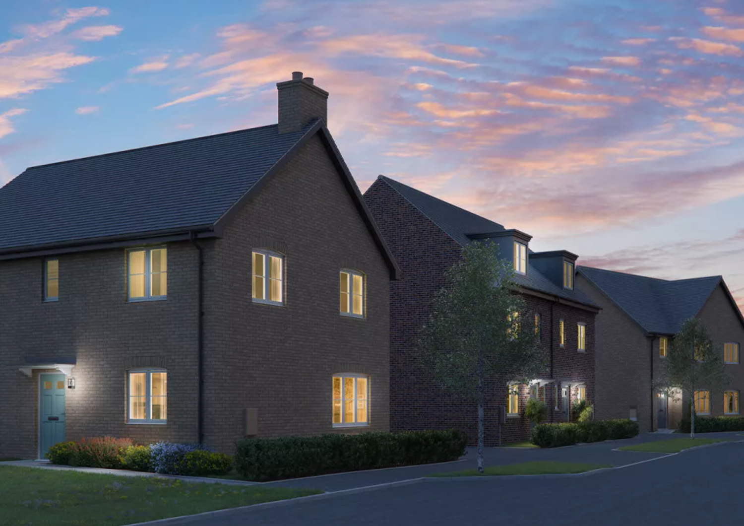 Modern brick residential homes illuminated at dusk with warm glowing windows against a dramatic pink and blue evening sky.