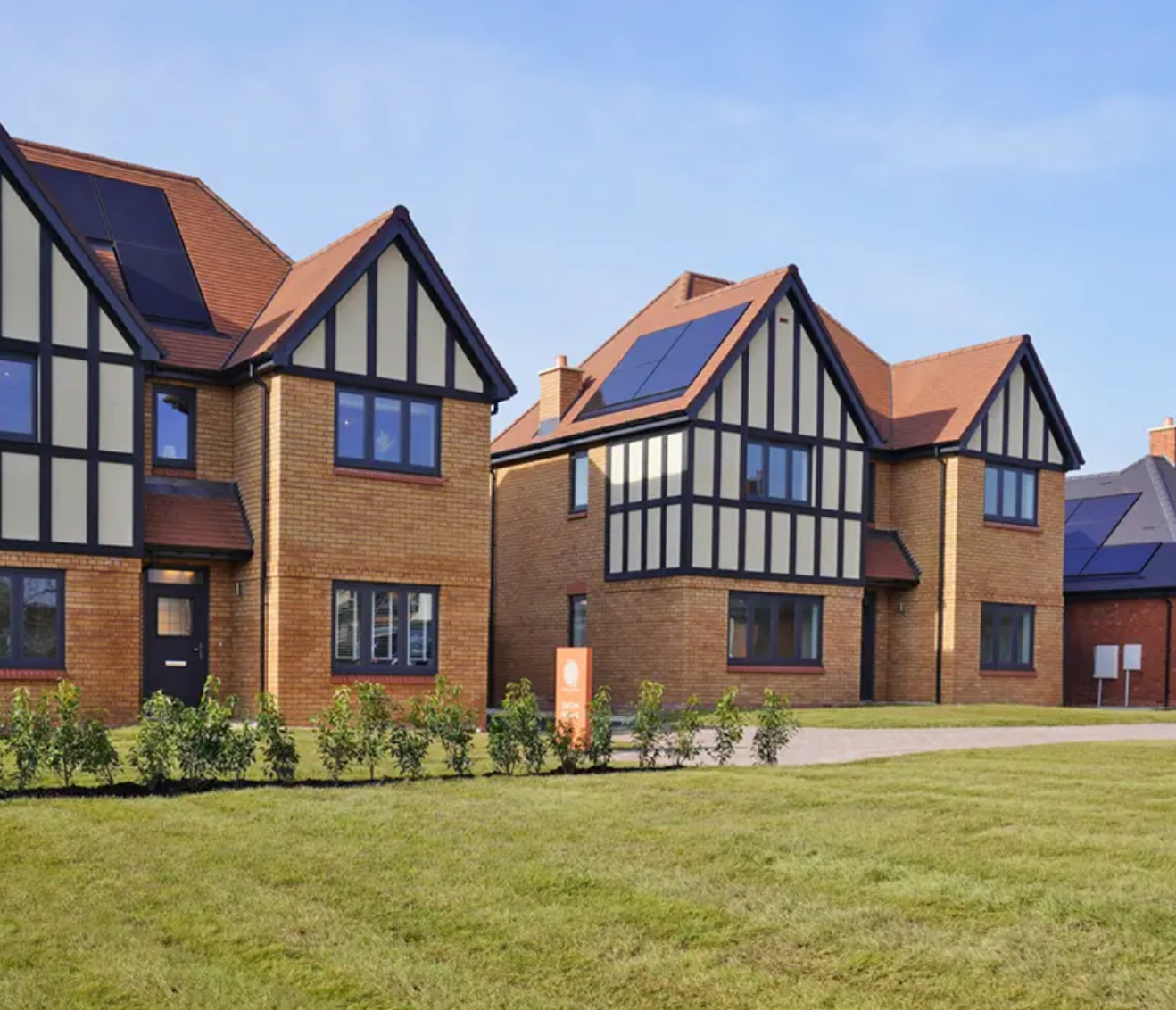 Modern Tudor-style brick homes with solar panels and manicured lawns in a new residential development.