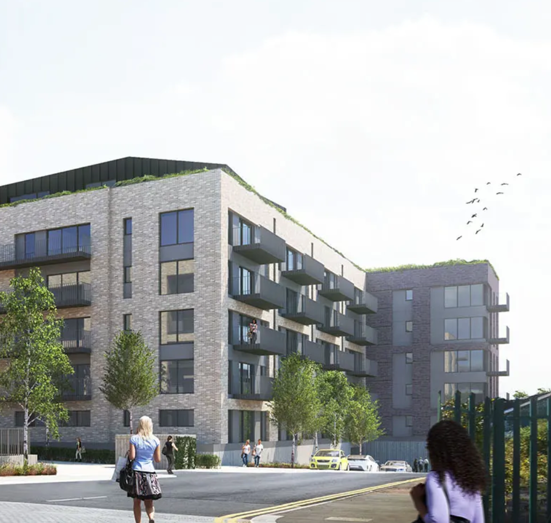 Modern residential apartment complex with brick facade, balconies, and rooftop greenery in an urban setting.
