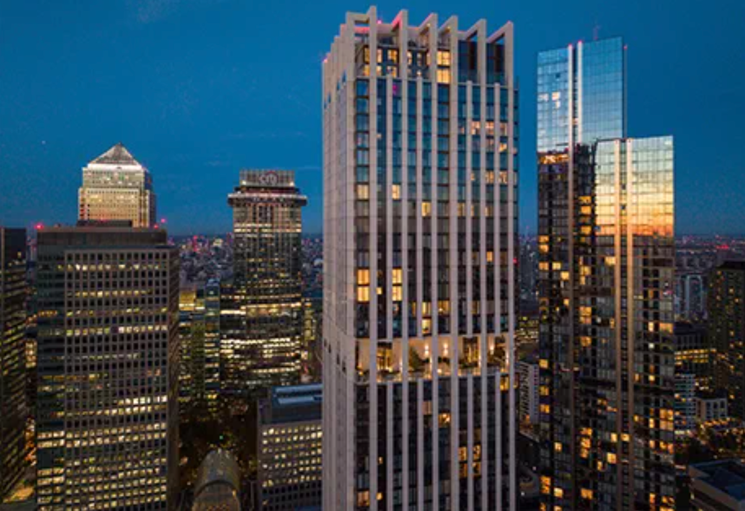 Aerial view of illuminated Manhattan skyscrapers at dusk with a colorful twilight sky backdrop.