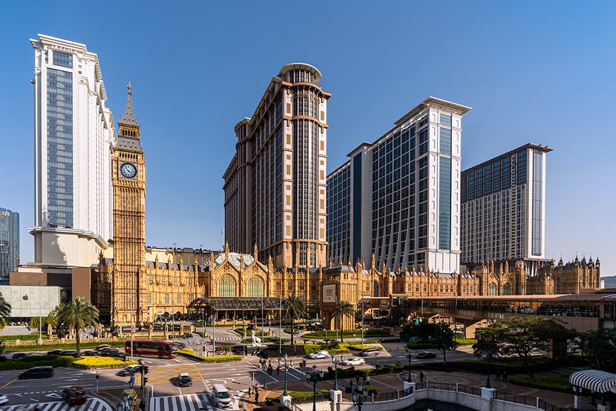 Luxury hotel complex with Big Ben replica and modern skyscrapers under clear blue sky in Macau, China.