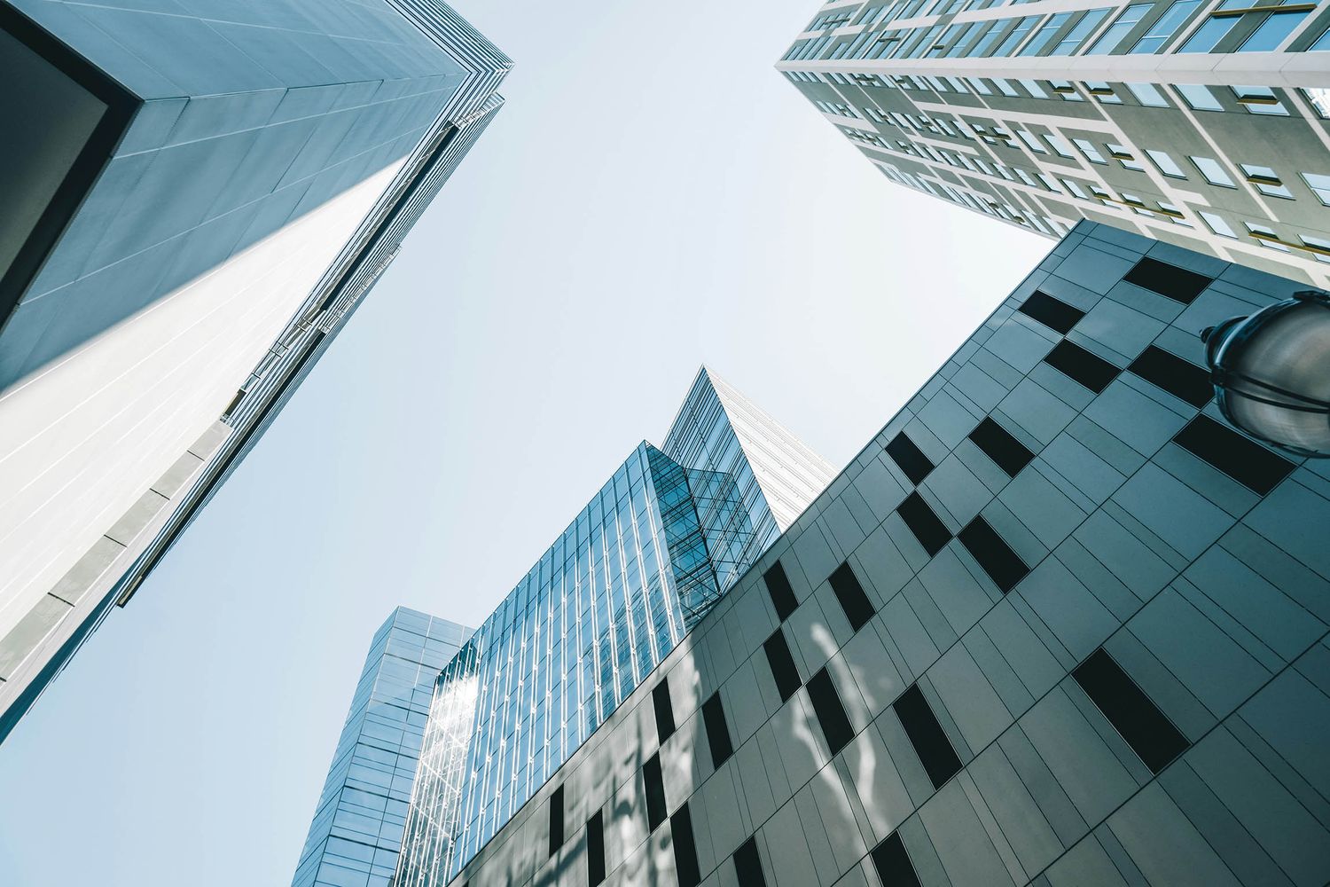 Low-angle view of modern glass skyscrapers reaching into a clear blue sky in an urban financial district.