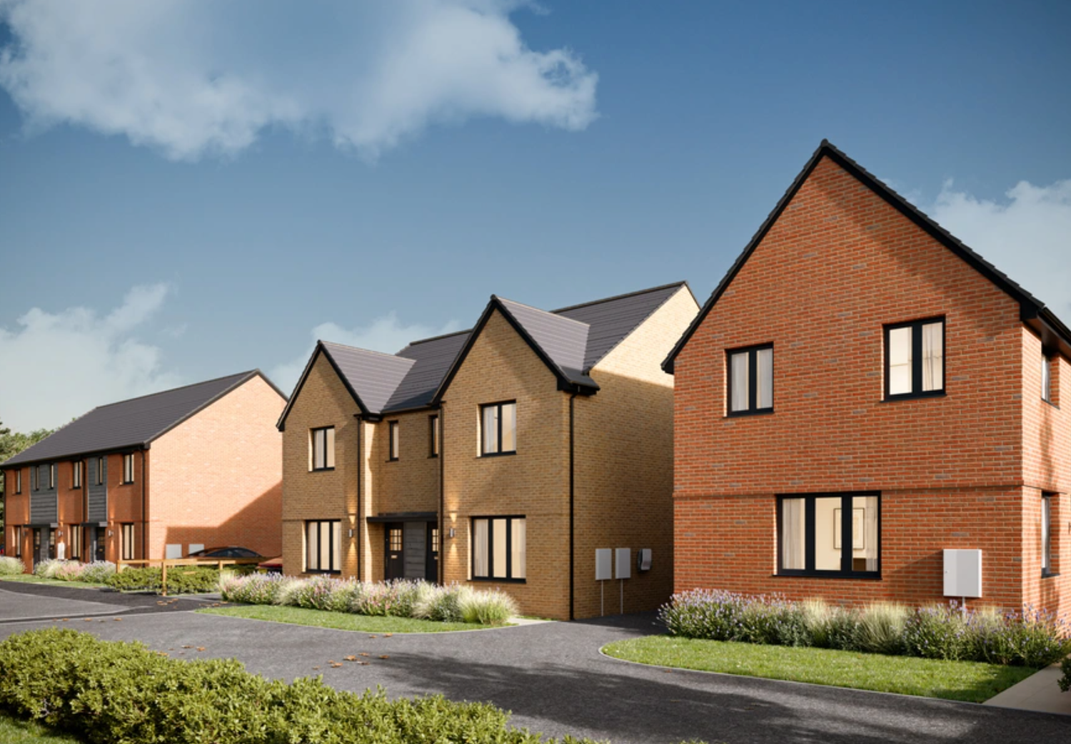 New build brick residential homes with grey roofs and manicured lawns on a sunny day in a modern UK housing development.