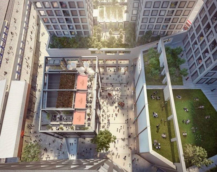 Aerial view of a modern urban plaza with pedestrians, green spaces, and surrounding high-rise buildings in a city development.
