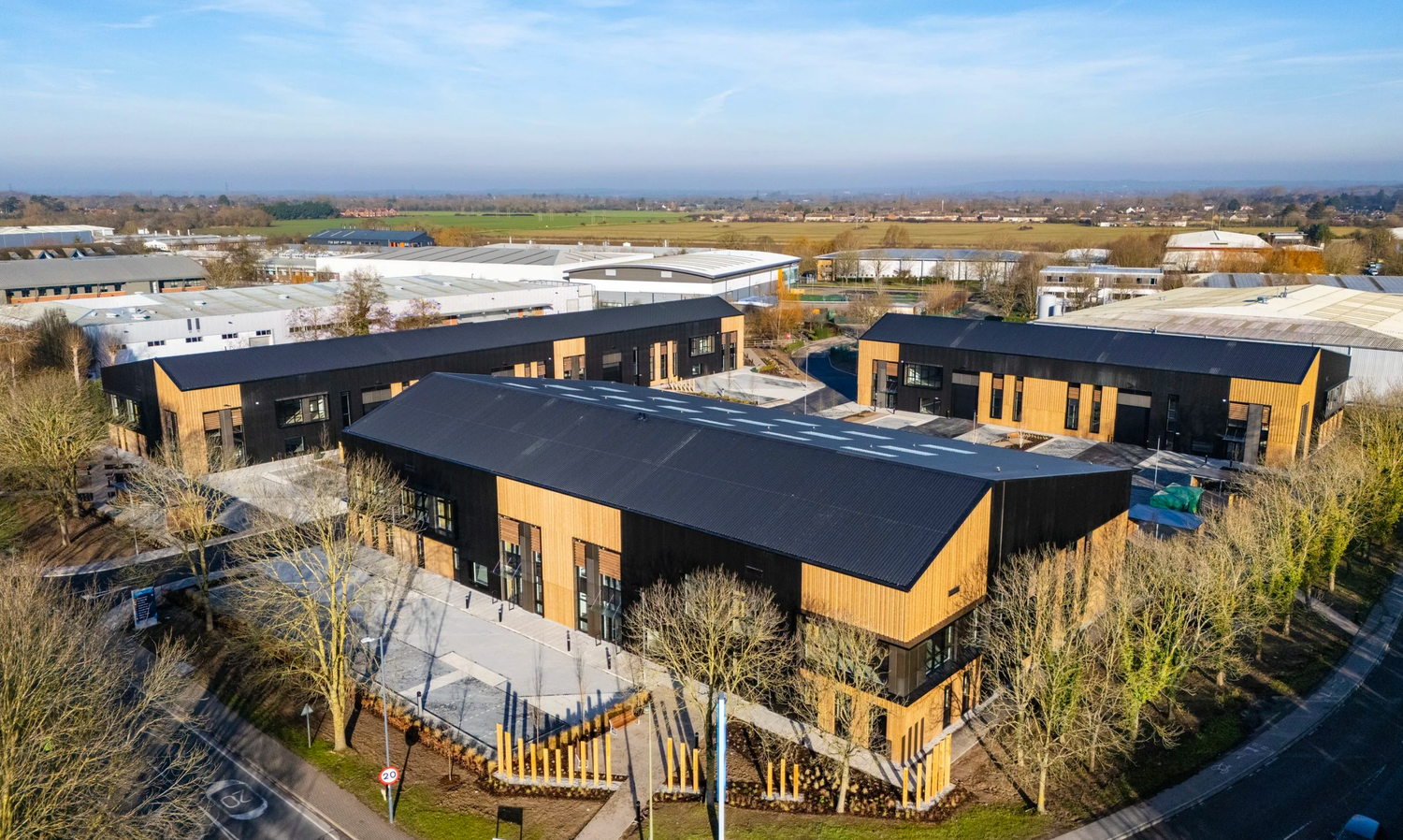 Aerial view of modern commercial buildings and parking lots in an industrial park setting.